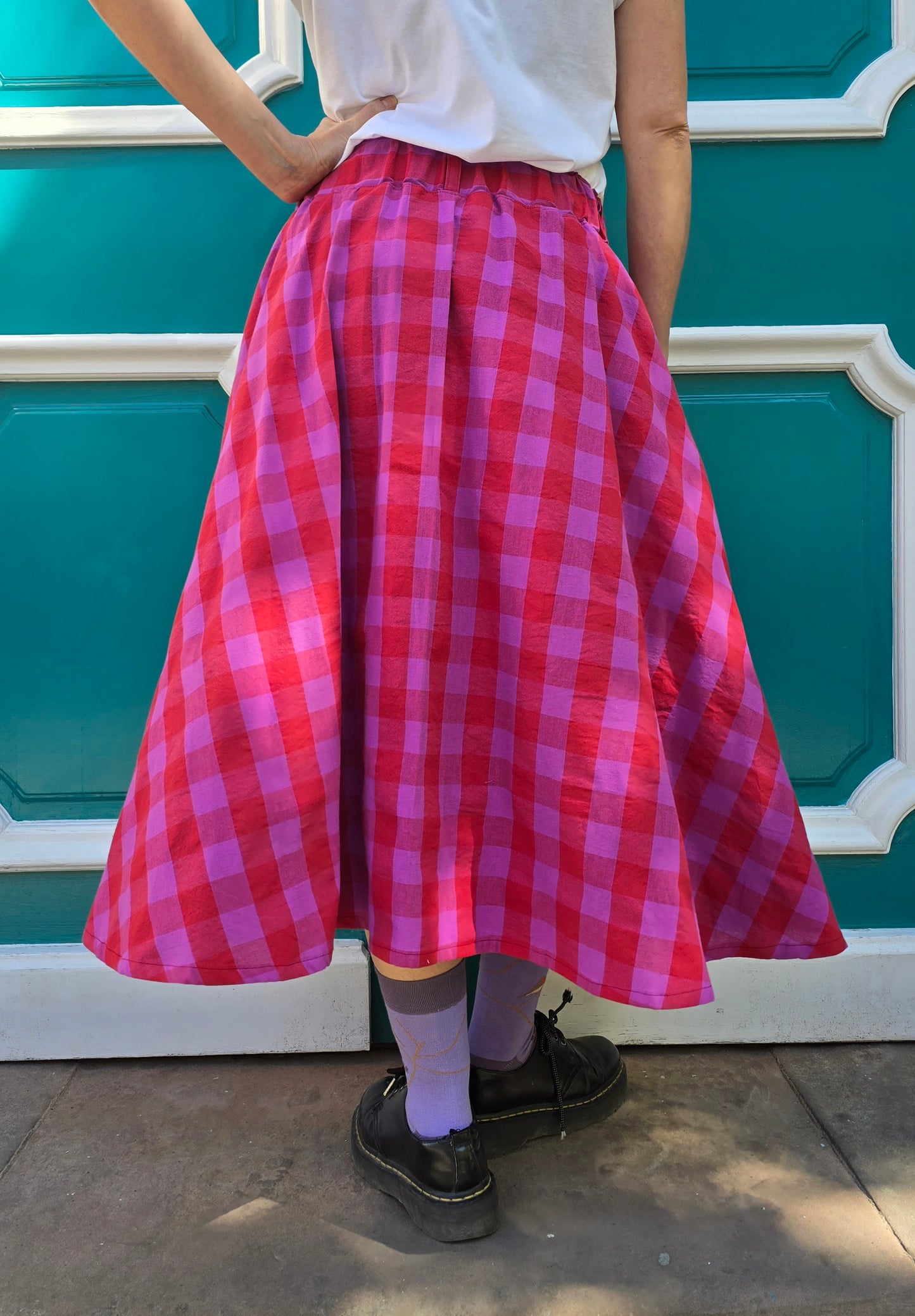 Weit schwingender Damenrock mit Karomuster in rot und lila, seitliche Eingrifftaschen und elastischer Bund.
