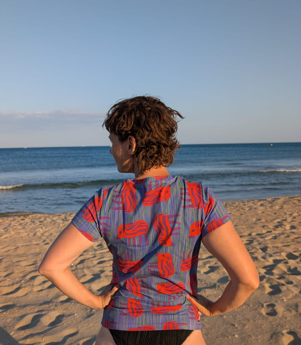 T-Shirt mit Wilder Wutz Frischling Aufdruck in orange und gestricheltem multicolor Hintergrund.