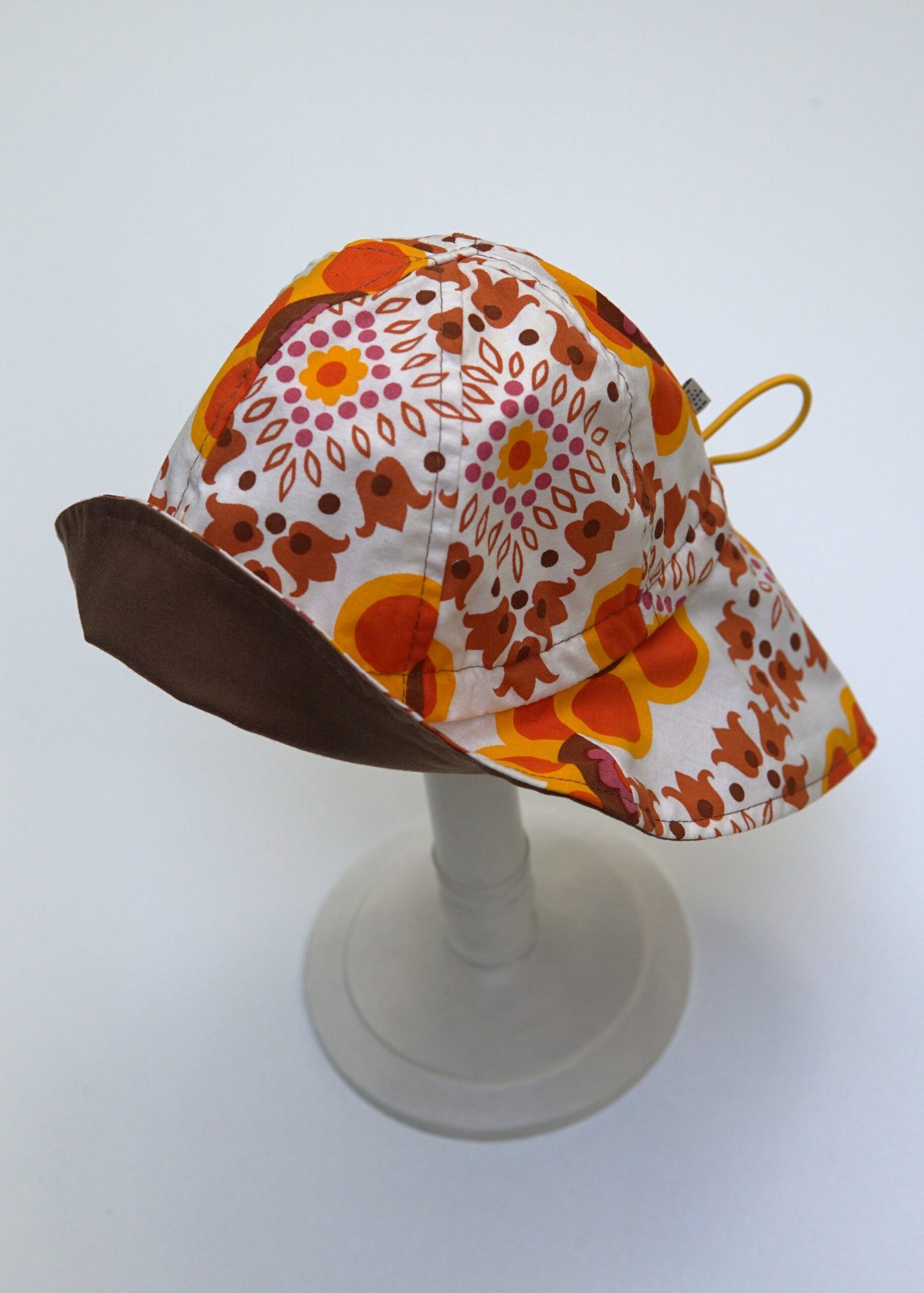 Toller Sonnenhut für Kinder mit Retro -Blumenmuster, in den Farben gelb, orange und braun. Schützt den Kopf nicht nur vor der Sonne, sondern ist auch noch ein stilvolles Accessoire.