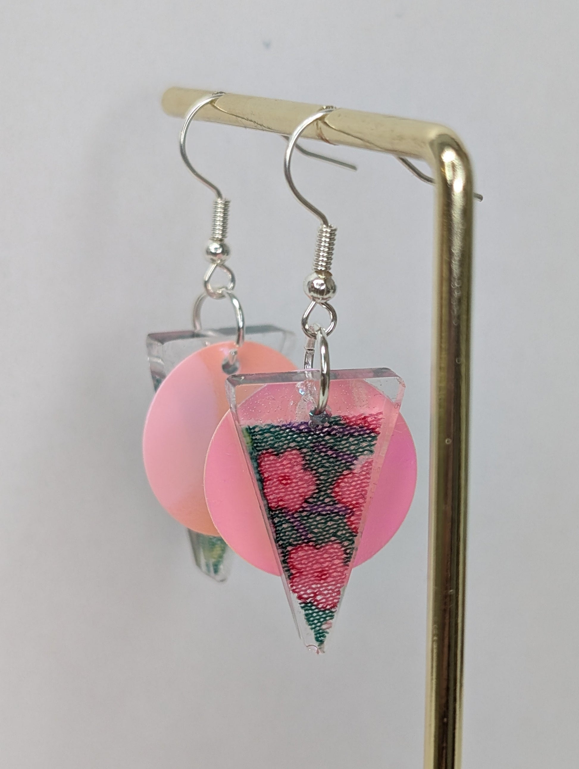 Stilvolle Ohrringe in Dreiecksform mit eingefügtem Blumenmusterstoff, in den Farben rosa und gruen.