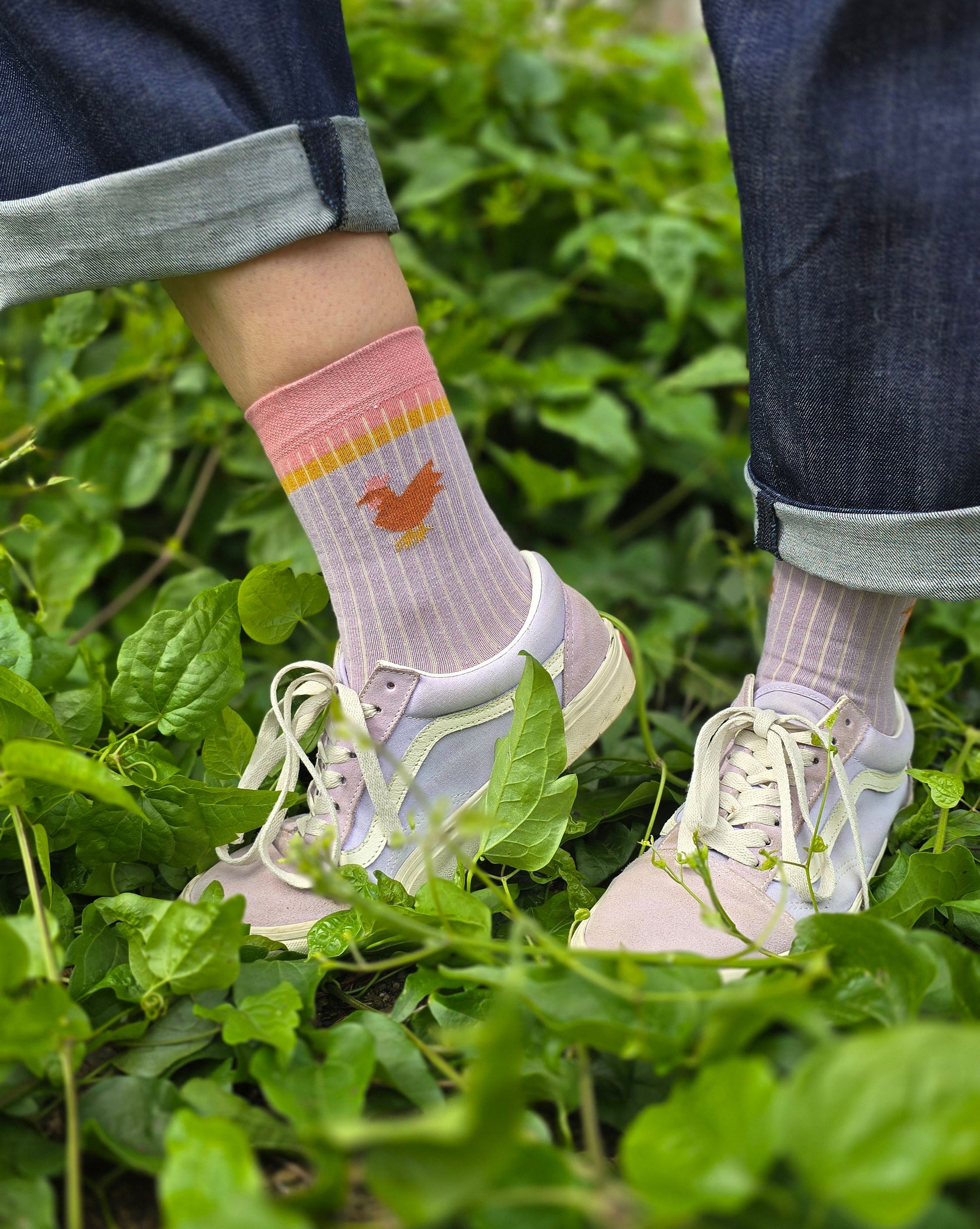 Socke im ColourblockStyle in lila pink und gelb mit kleinem Huhn seitlich.