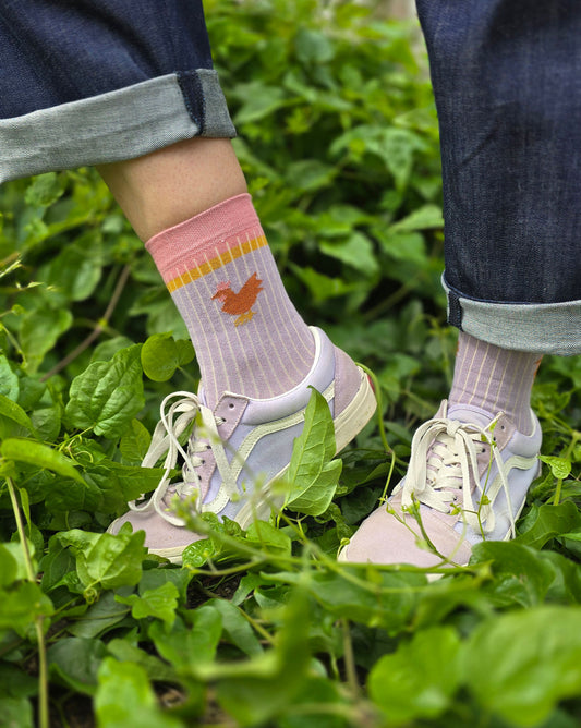 Socke im ColourblockStyle in lila pink und gelb mit kleinem Huhn seitlich.