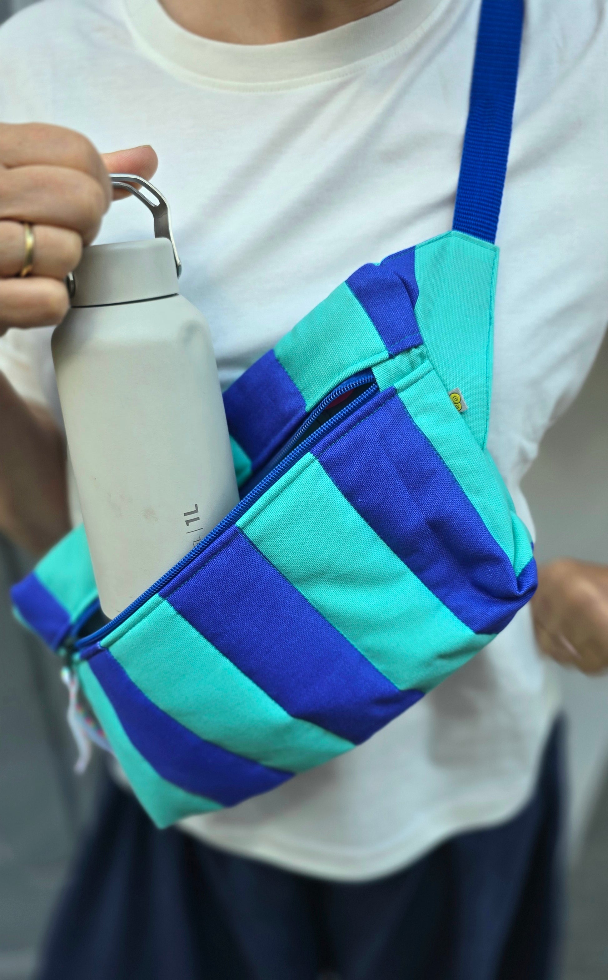 Rechteckige Handtasche oder Bauchtasche mit verstellbarer Schnalle, weich wattiert aus Canvas, fester Baumwolle mit Blockstreifen und Reißverschluss blau und türkis.