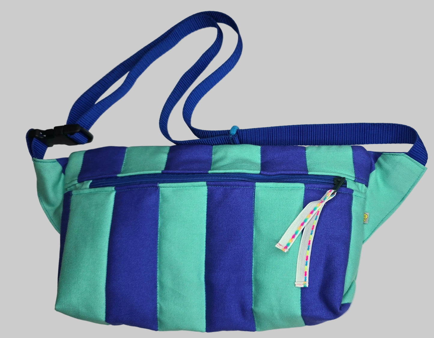 Rechteckige Handtasche oder Bauchtasche mit verstellbarer Schnalle, weich wattiert aus Canvas, fester Baumwolle mit Blockstreifen und Reißverschluss blau und türkis.
