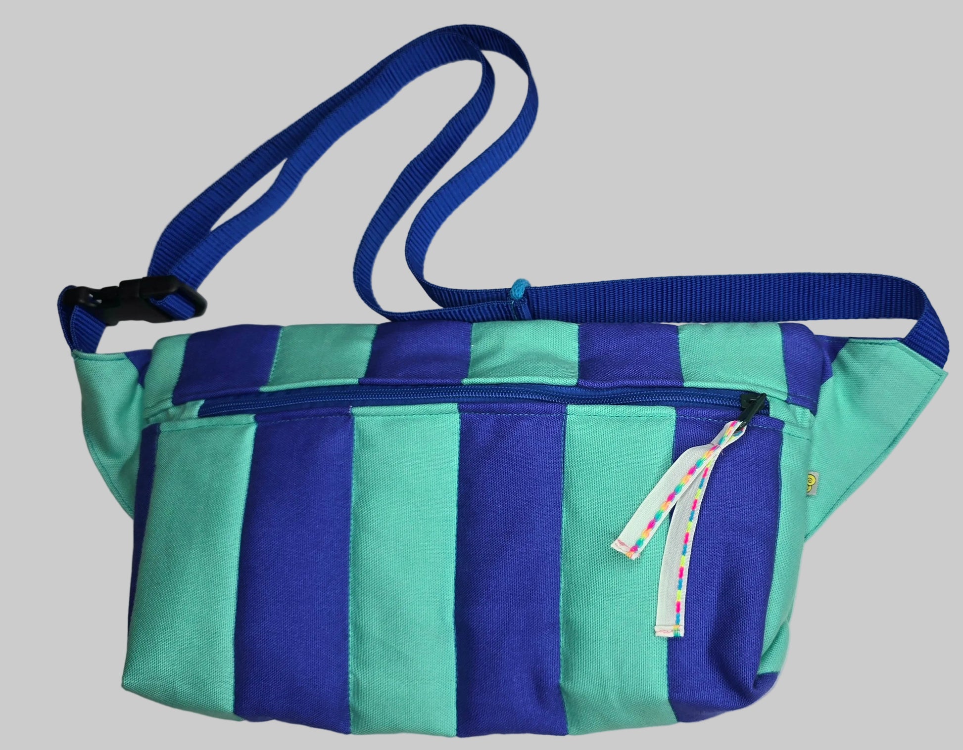 Rechteckige Handtasche oder Bauchtasche mit verstellbarer Schnalle, weich wattiert aus Canvas, fester Baumwolle mit Blockstreifen und Reißverschluss blau und türkis.
