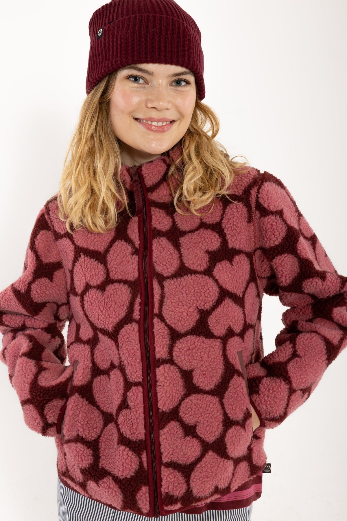 Jacke aus Teddyplüsch, klassisch gerader Schnitt mit kleinem Stehragen und Herzen Muster in Dunkelrot und Pink.