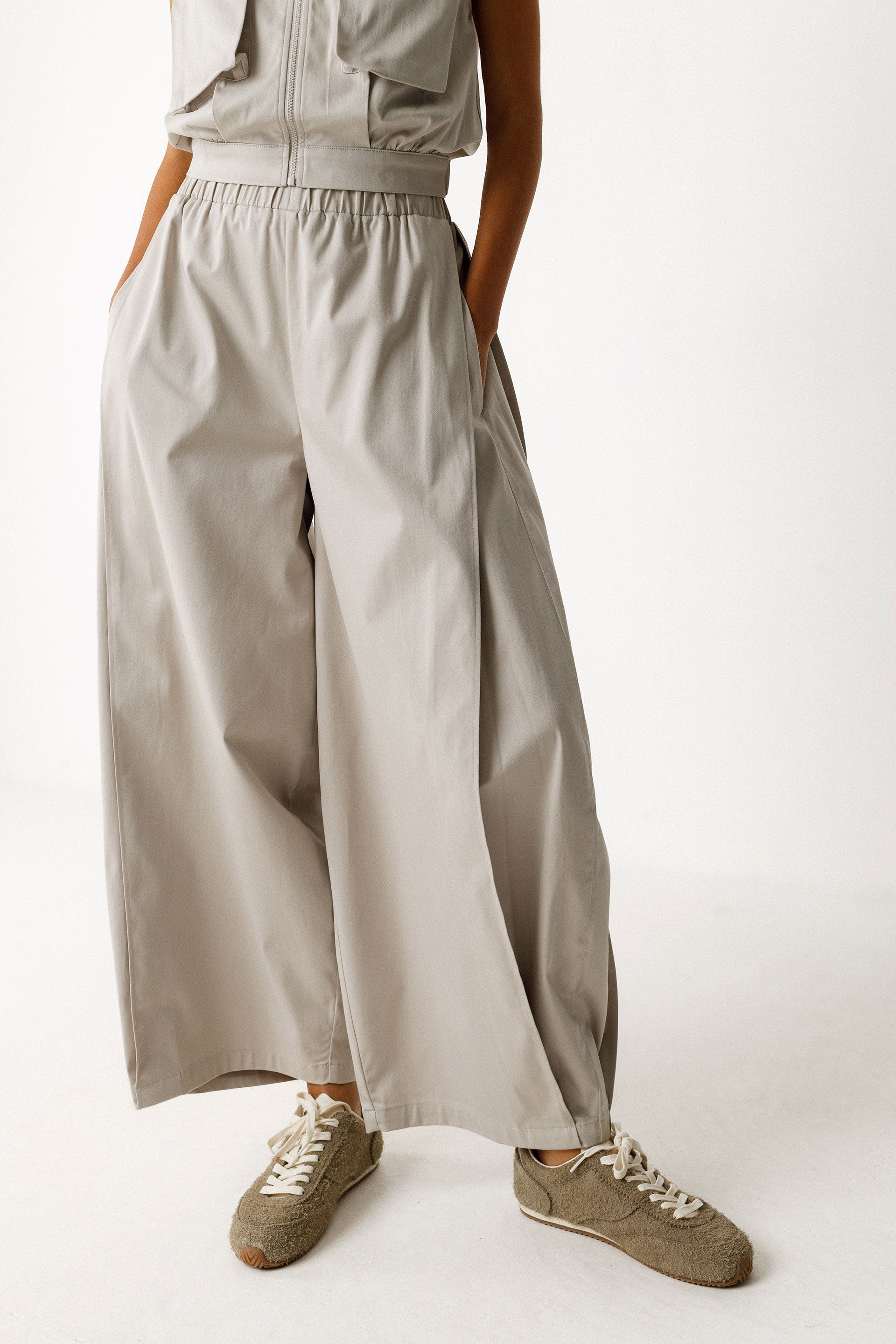 Damenhose in beige grau mit gelegten Falten von Saum bis Taille in Ballonoptik aus glatter Biobaumwolle.