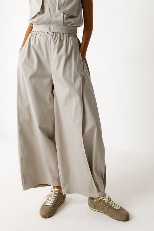 Damenhose in beige grau mit gelegten Falten von Saum bis Taille in Ballonoptik aus glatter Biobaumwolle.