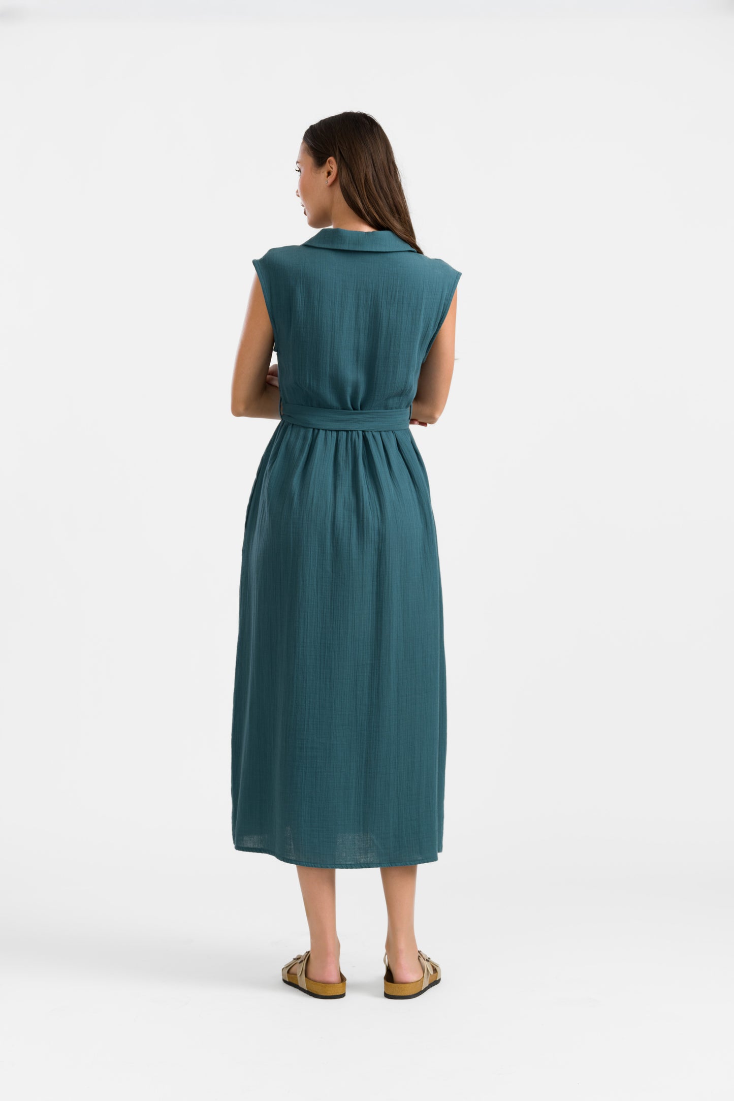 Kleid mit Kragen und frontaler Knöpfung, Bindegürtel und seitliche Eingrifftaschen in Petrol, das Kleid ist wadenlang und ärmellos.