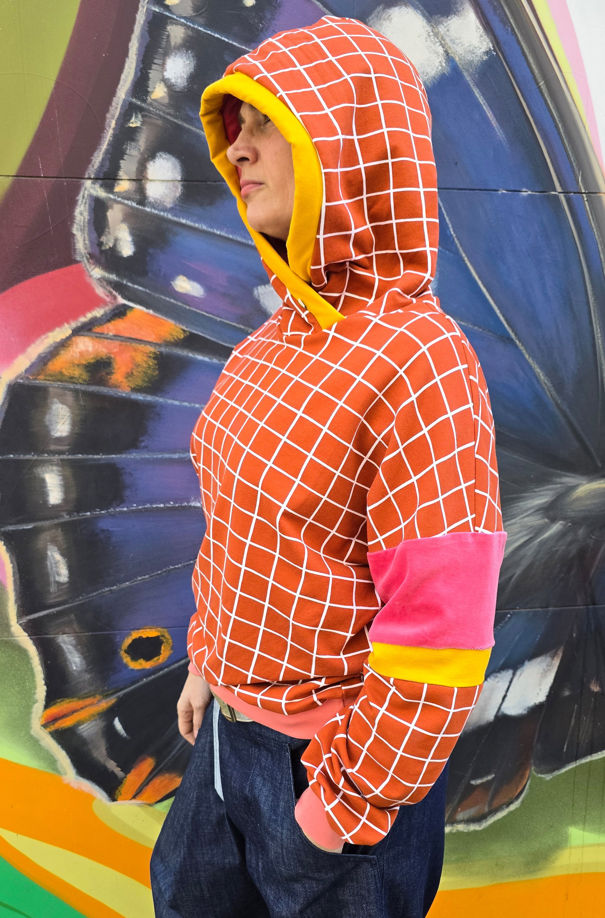 Kapuzen Sweatshirt mit GridMuster in orange und weiss, die Kapuze hat einen Gelbakzent und innen ist sie aus pink Nicky, Bündchen sind apricot.