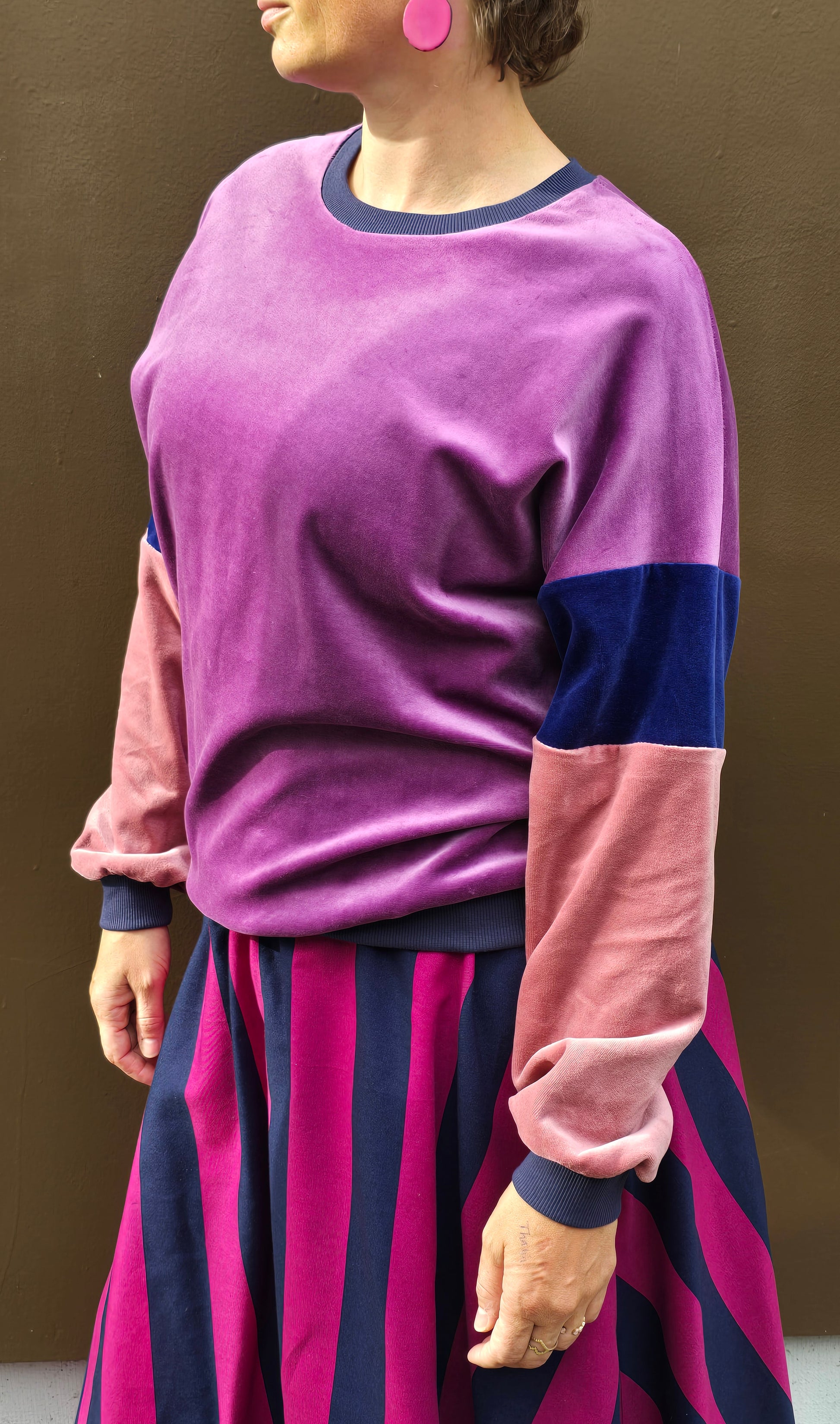 Kuschelig weicher Nicky Pullover im klassischen Sweatshirt Style mit überschnittener Schuter, lila, blau und rosa mit dunkelblau Bündchen.