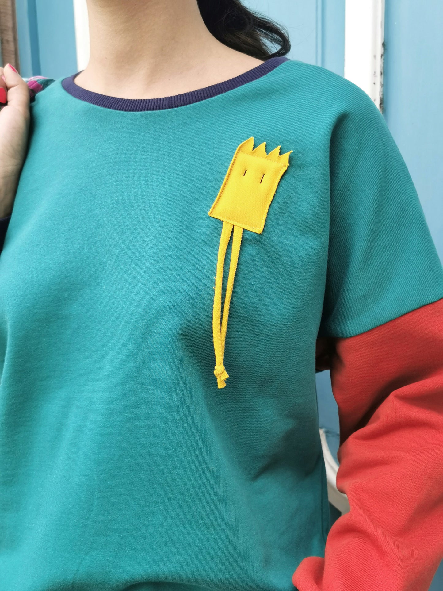 Sweatshirt mi lustigem Männchen als Applikation in Brusthöhe,türkuis und orange