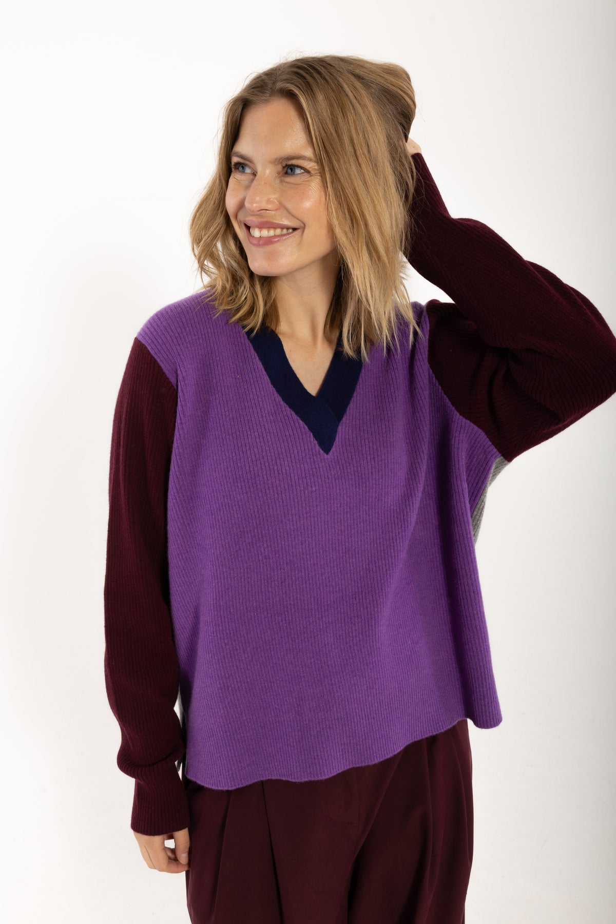 Locer und gerade geschnittener Pullover im Colourblock Design mit bordeaux Ärmeln, grau Rückenteil und fresh lila Front aus feinster Merinowolle.