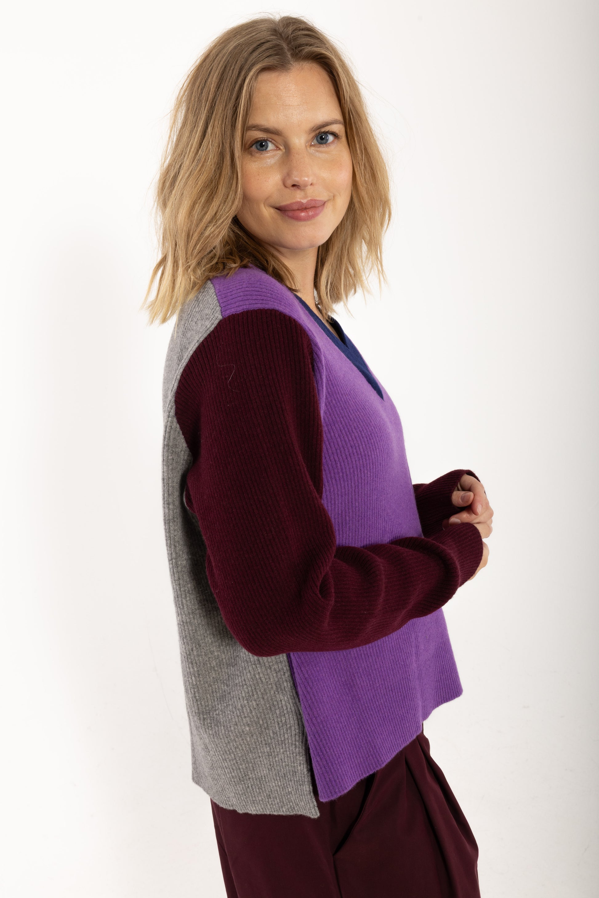 Locer und gerade geschnittener Pullover im Colourblock Design mit bordeaux Ärmeln, grau Rückenteil und fresh lila Front aus feinster Merinowolle.