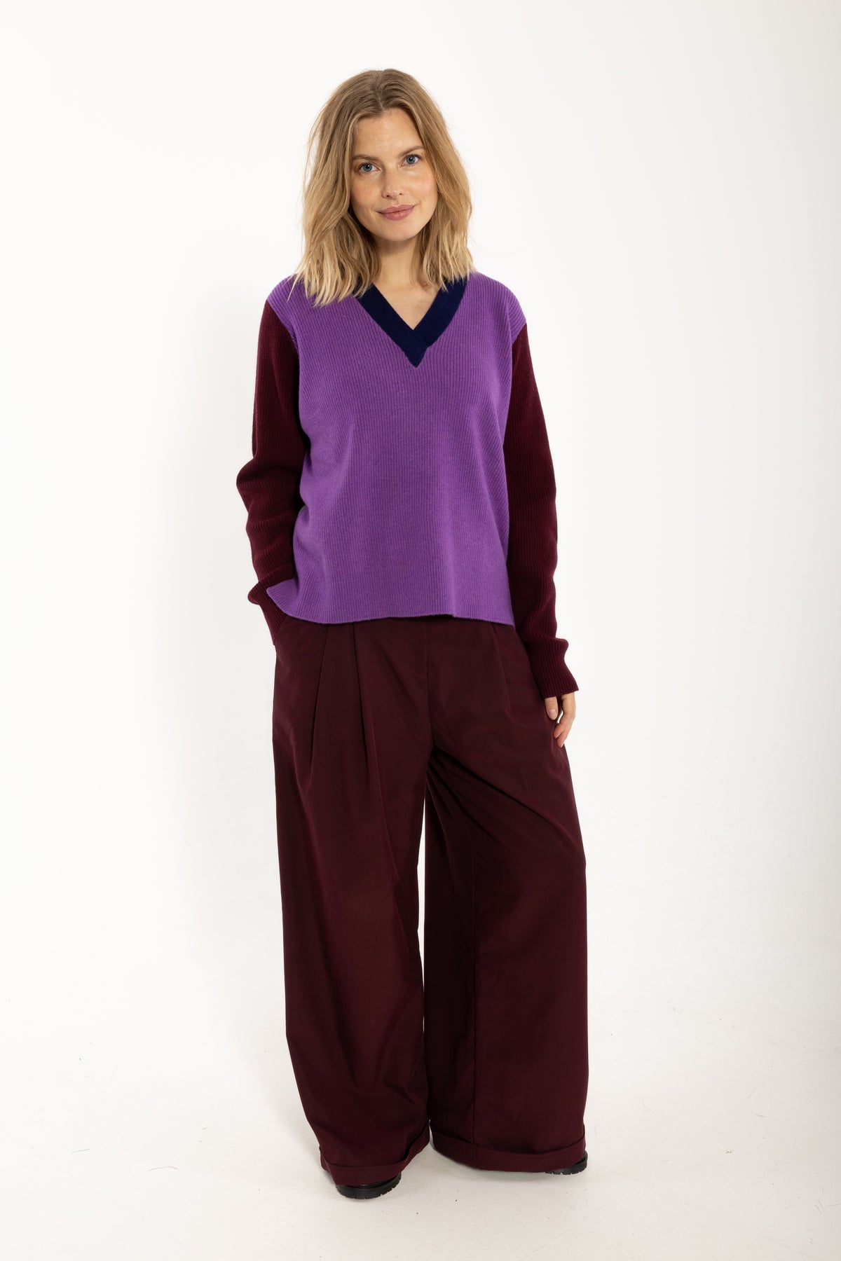 Locer und gerade geschnittener Pullover im Colourblock Design mit bordeaux Ärmeln, grau Rückenteil und fresh lila Front aus feinster Merinowolle.