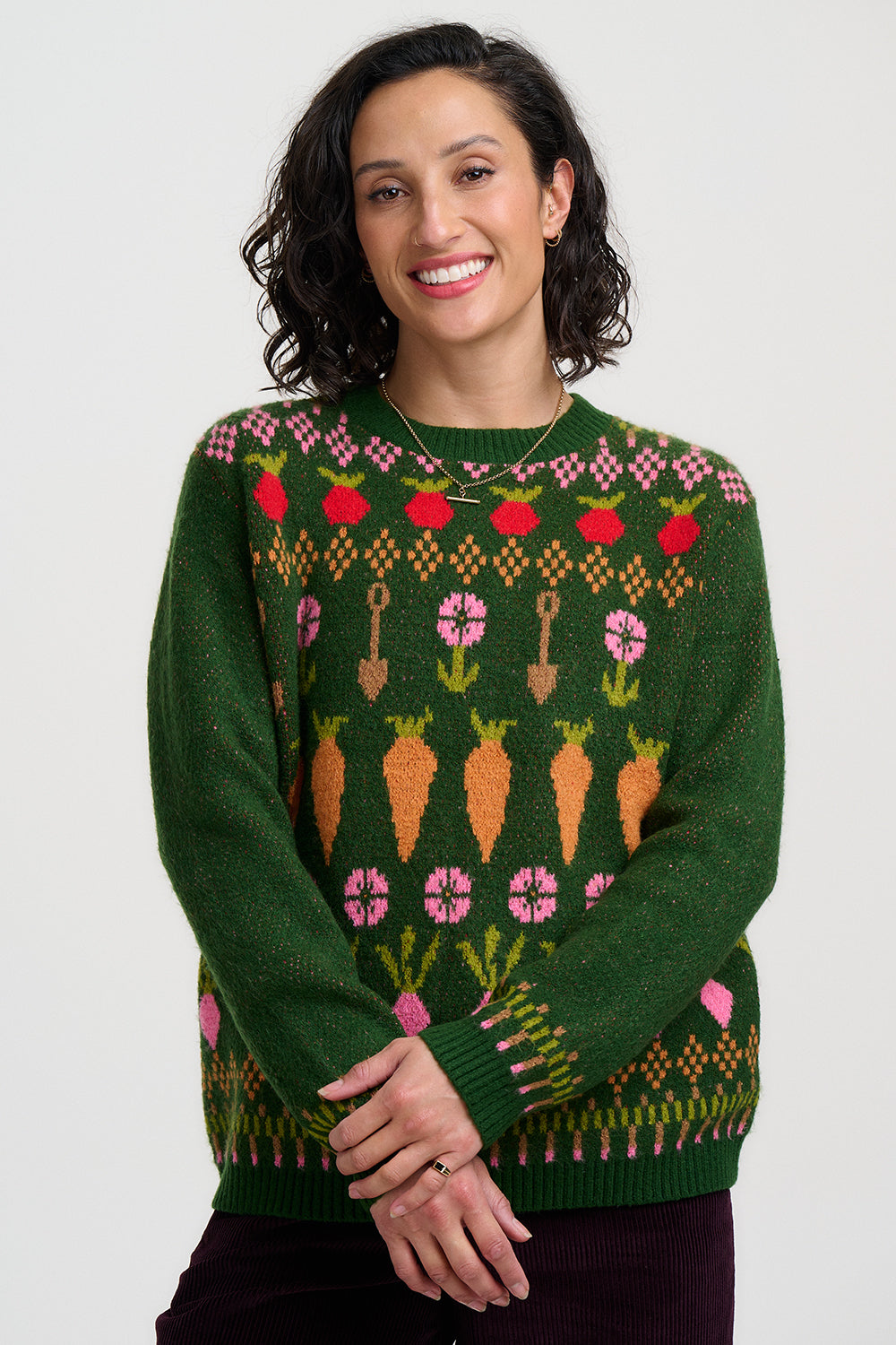 Strickpullover in dunklem Grün mit buntem Gmüse in Fairisle Stickreihen, Möhren, Radiesschen und Rüben, sowie Spaten und Blümchen reihen sich aneinander im witzigen Bauernhof Spirit.