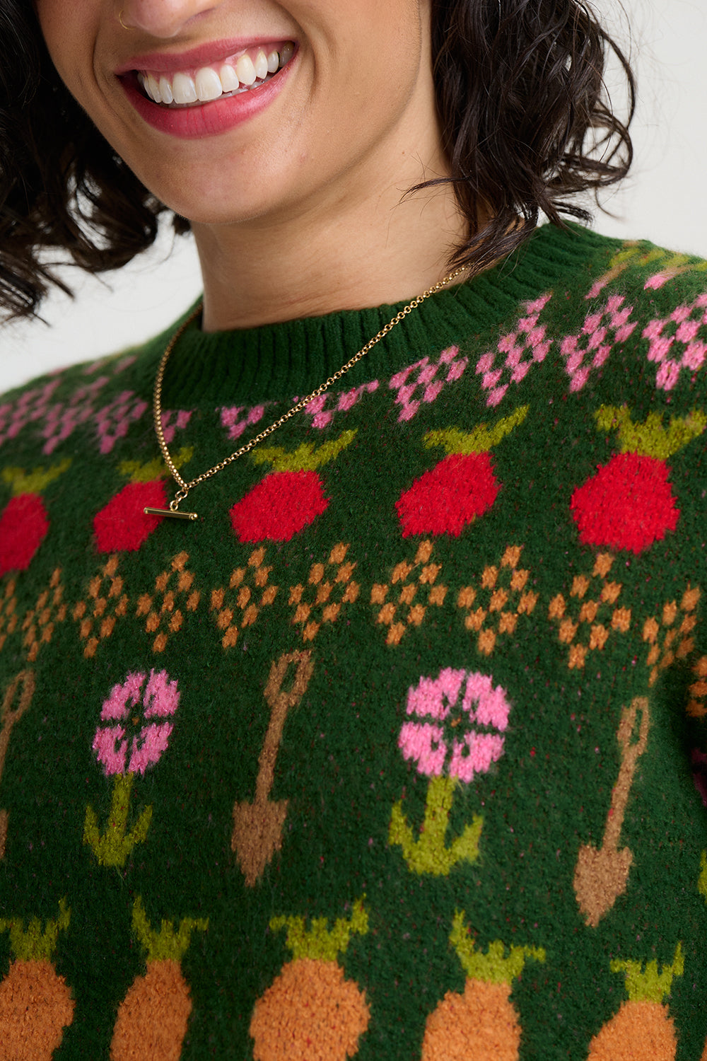Strickpullover in dunklem Grün mit buntem Gmüse in Fairisle Stickreihen, Möhren, Radiesschen und Rüben, sowie Spaten und Blümchen reihen sich aneinander im witzigen Bauernhof Spirit.