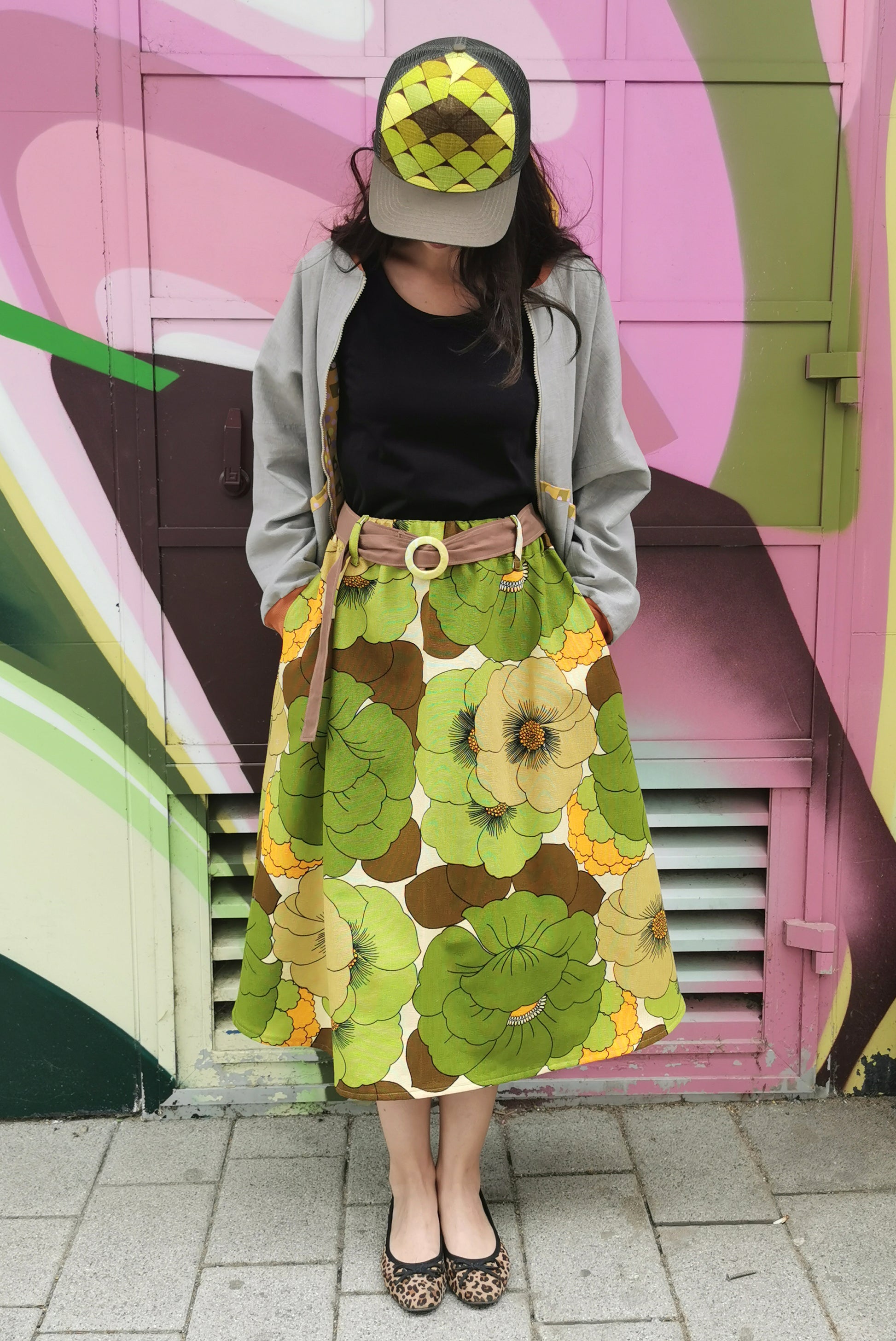 Große grüne retro Blumen auf weit schwingendem Rock mit seitlichen Eingrifftaschen und Stoffgürtel.