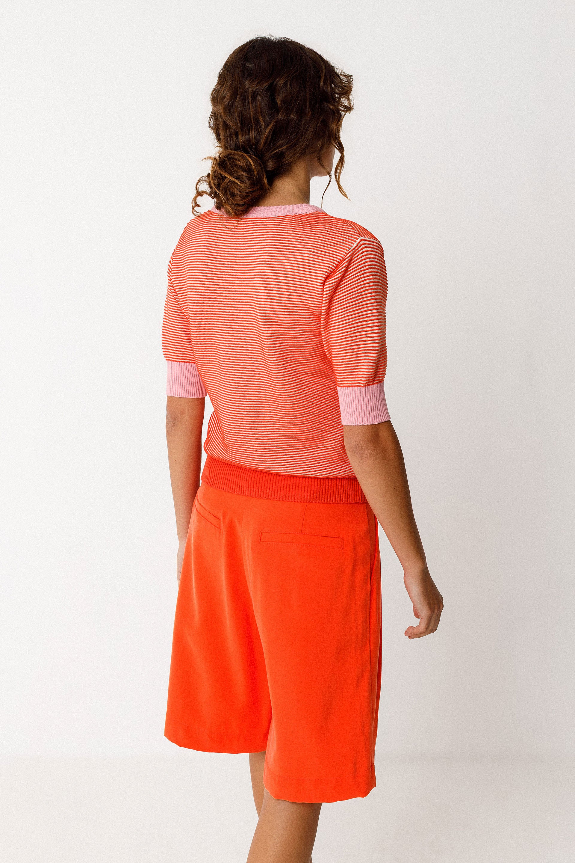 Kurzärmliges Damen Stricktop in Streifenoptik orange und rosa, mit rosa Armbündchen und Halsabschuss.