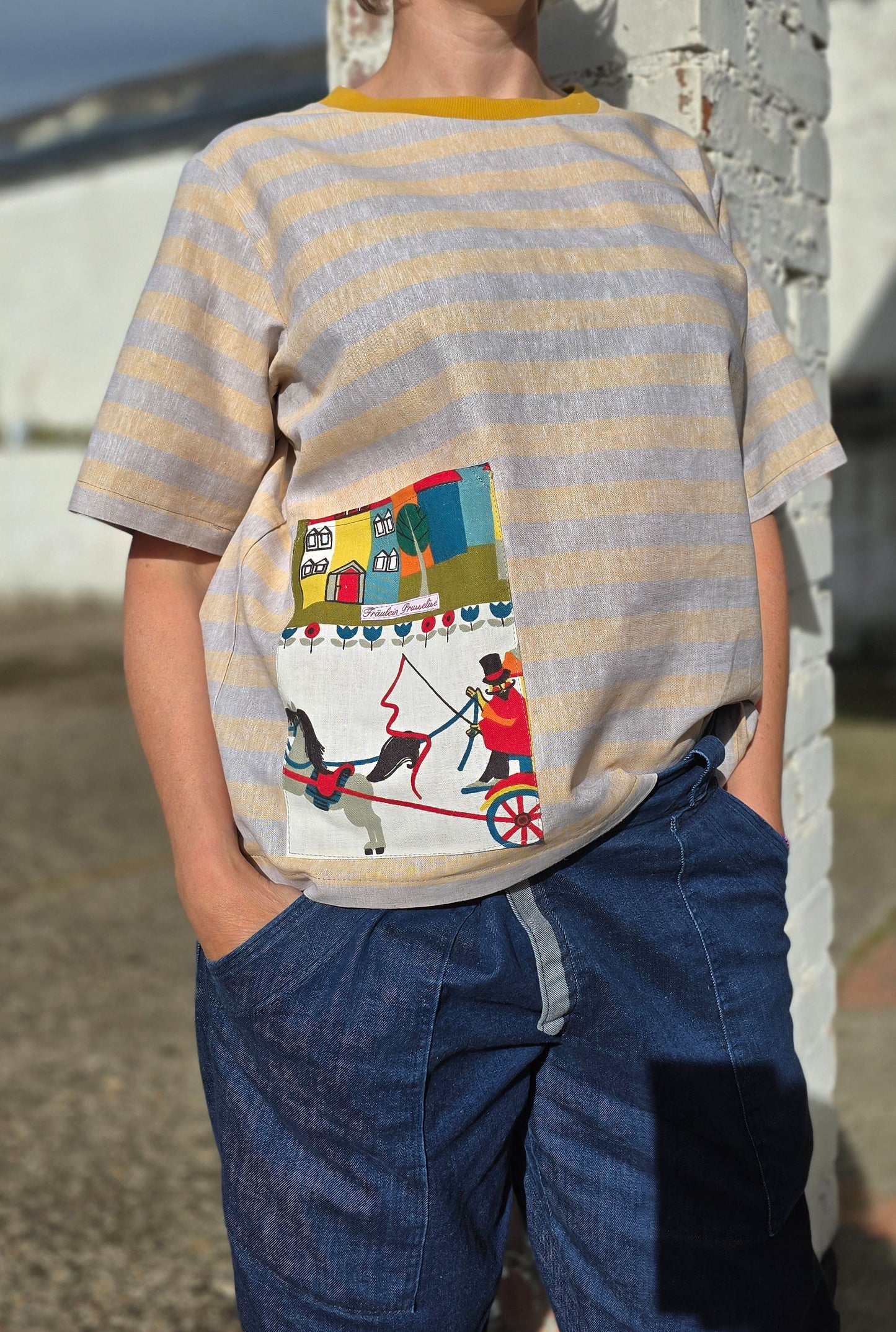 Loose Fit Shirt aus Leinen mit Baumwolle, Blockstreifen in Melange beige und gelb mit Aufsatztasche aus Landschafts Retrostoff mit Häuserzeile, Kutsche,Pferdchen,spielenden Menschen je nach Soffausschnitt.