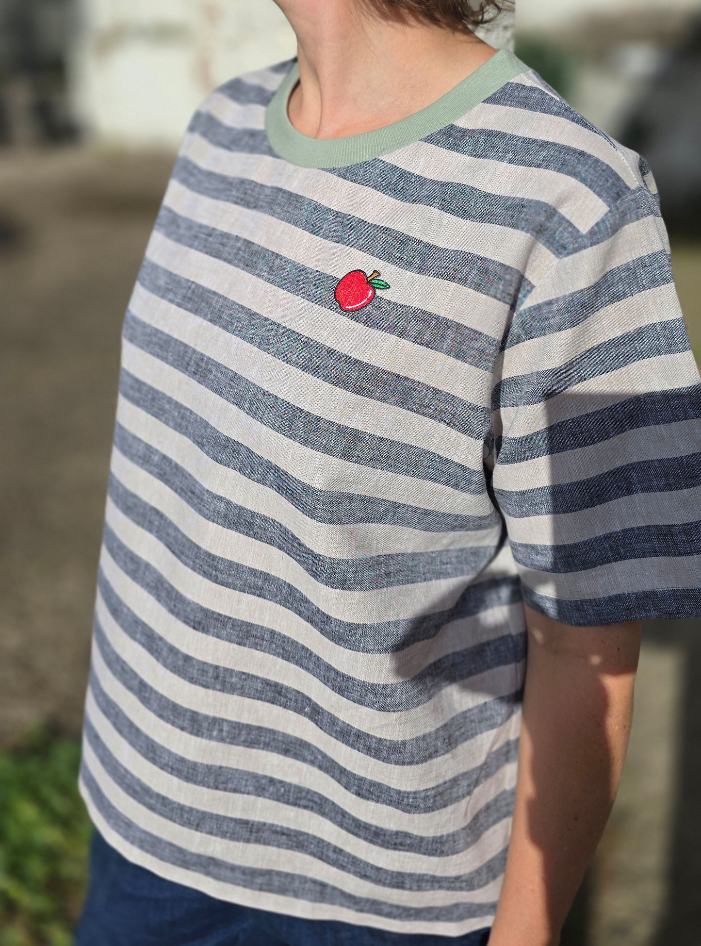 Loose Fit Shirt aus Leinen mit Baumwolle, Blockstreifen in Melange beige und schwarz mit rot Stickerei Äpfelchen Patch im Brustbereich.