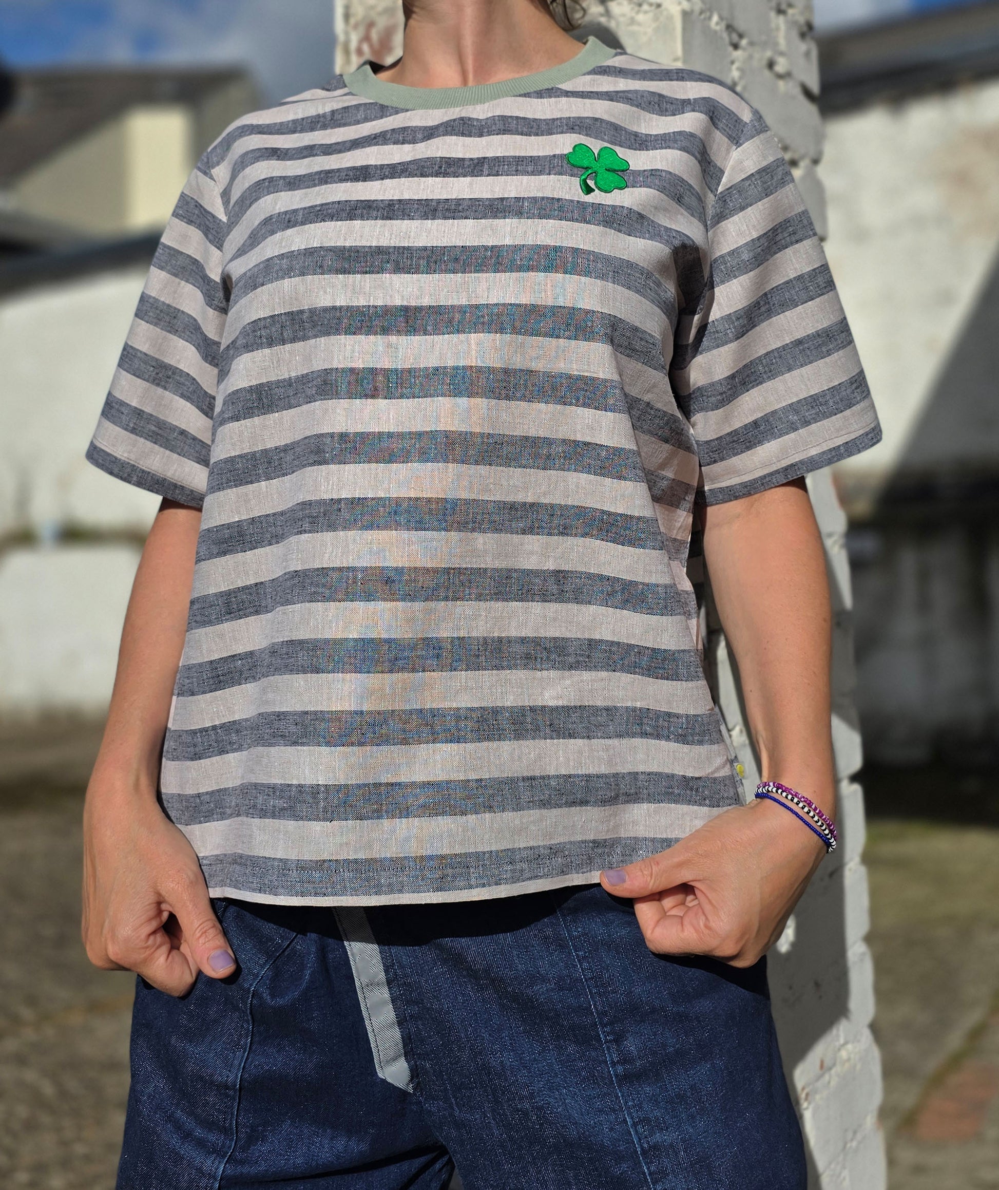 Loose Fit Shirt aus Leinen mit Baumwolle, Blockstreifen in Melange beige und schwarz mit Stickerei Kleeblatt Patch in grün.