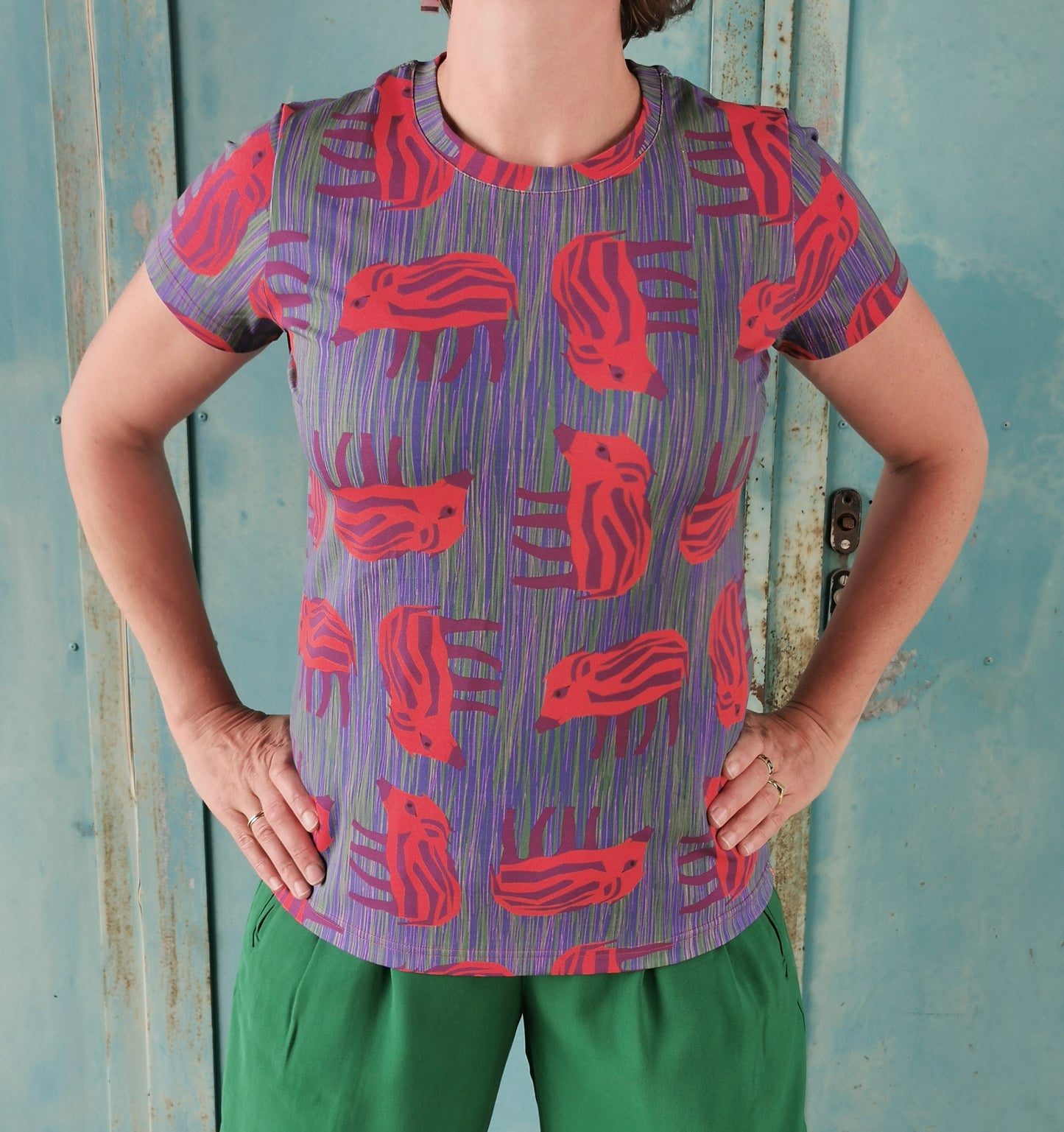 T-Shirt mit Wilder Wutz Frischling  Aufdruck in orange und gestricheltem multicolor Hintergrund.