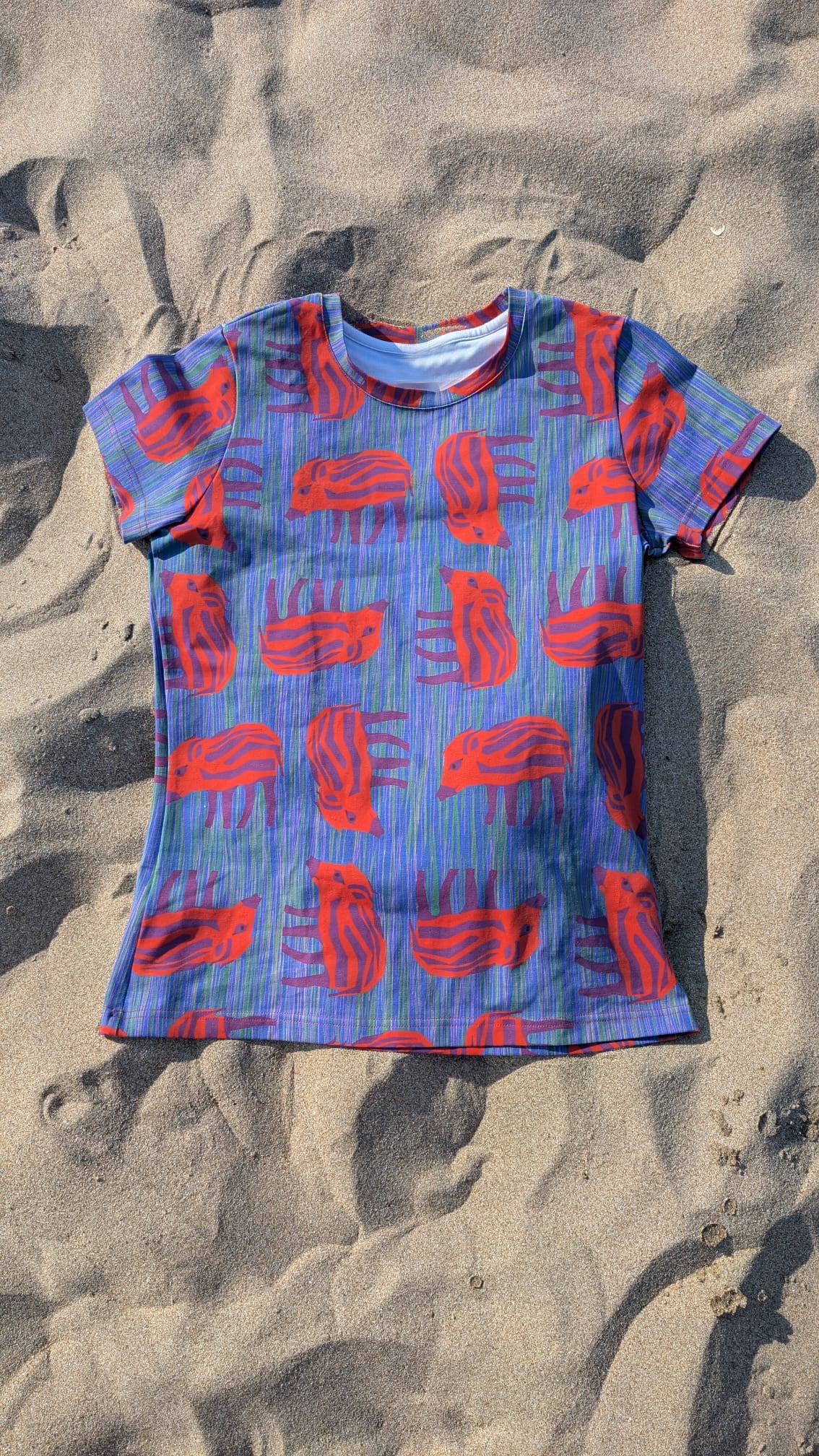 T-Shirt mit Wilder Wutz Frischling  Aufdruck in orange und gestricheltem multicolor Hintergrund.