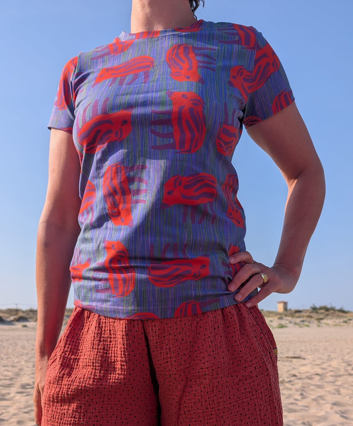 T-Shirt mit Wilder Wutz Frischling  Aufdruck in orange und gestricheltem multicolor Hintergrund.