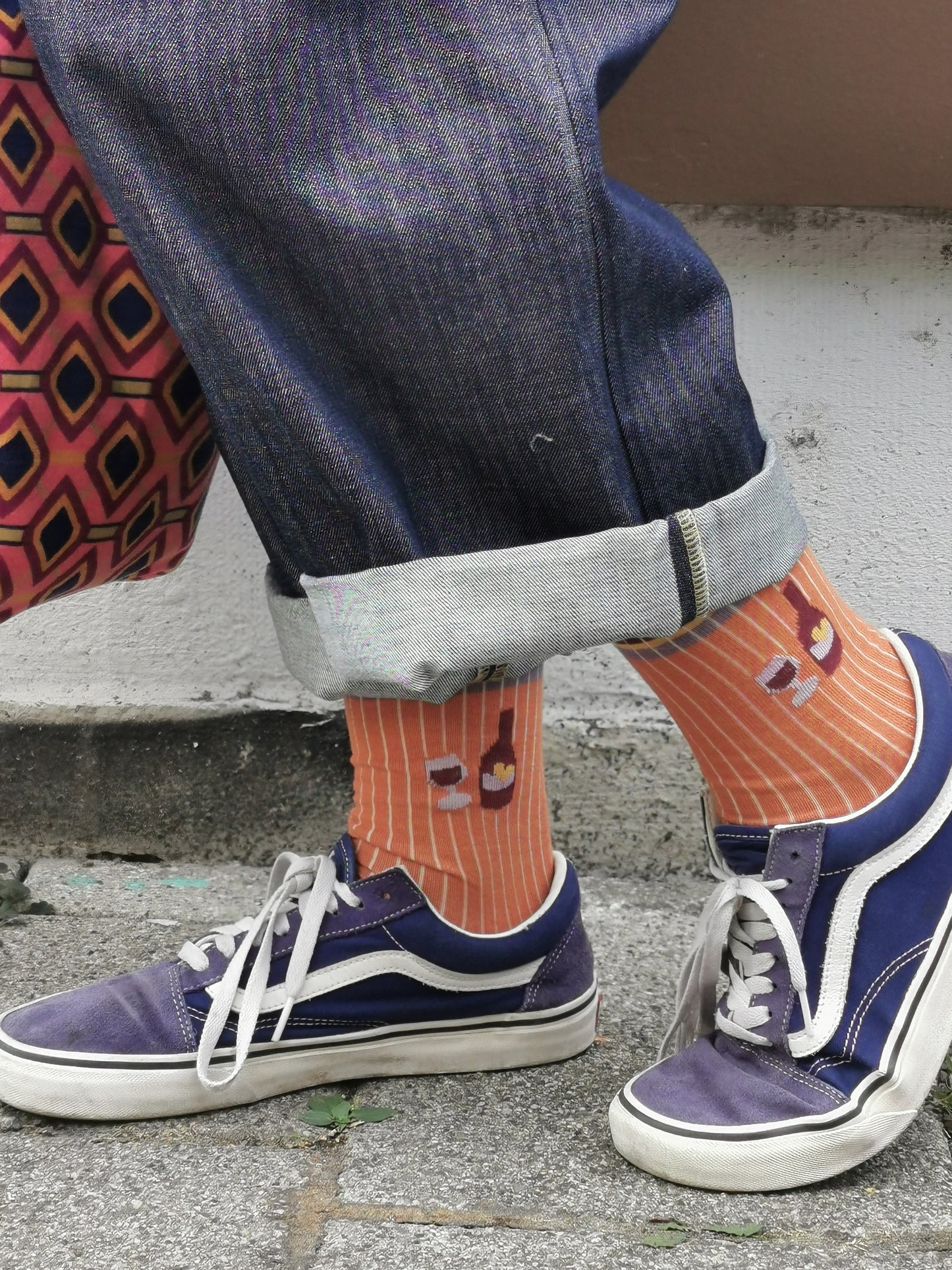 Wein Flasche un Glas auf einer zimt farbenen Socke in Ripp Strick mit colourblock Akzenten in bordeau, lila und gelb.