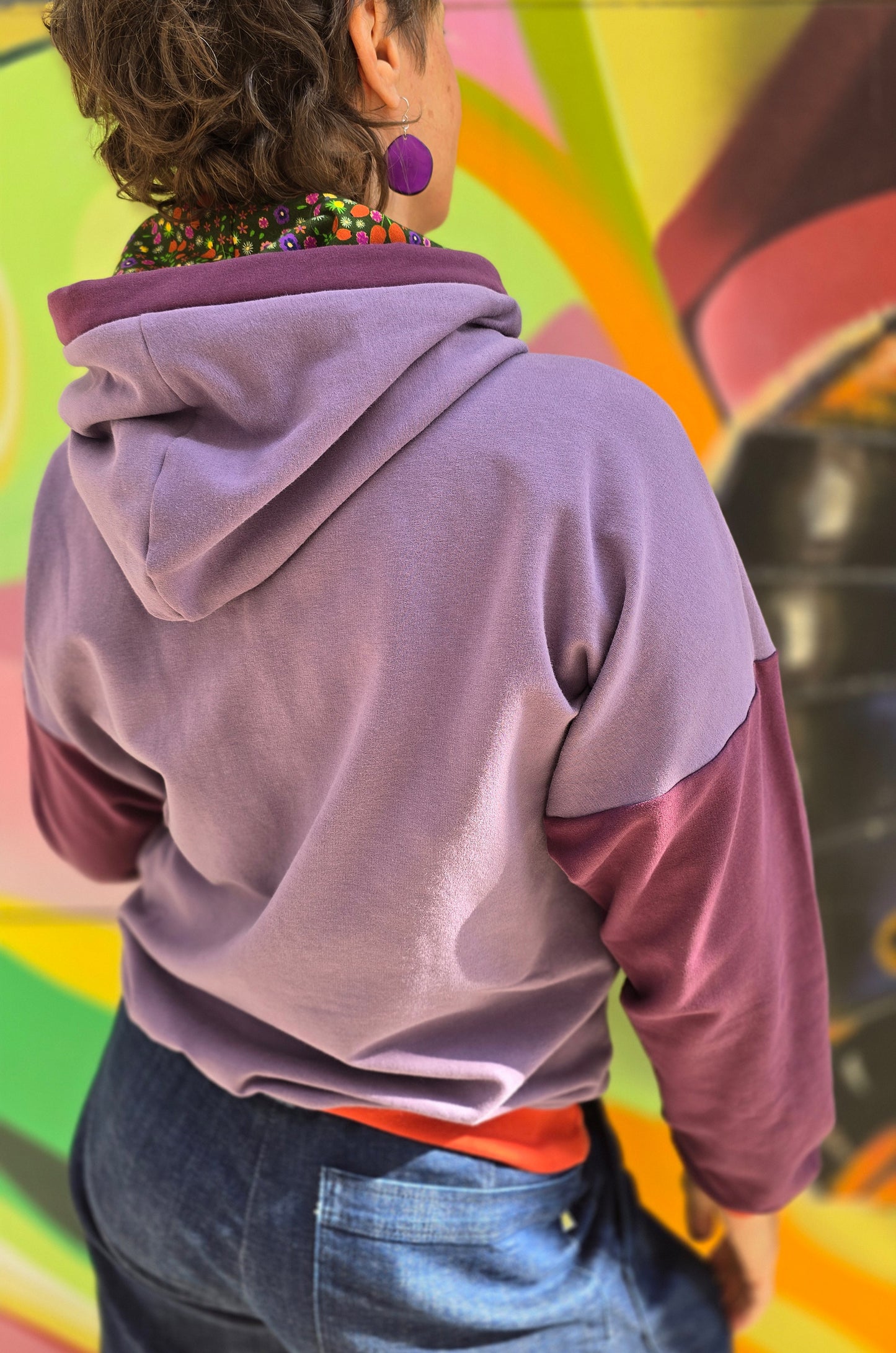 Hoody im Colourblock Design mit orange Bündchen, lila Ärmeln und in der lila Kapuze ist Millefleurs Jersey verarbeitet.