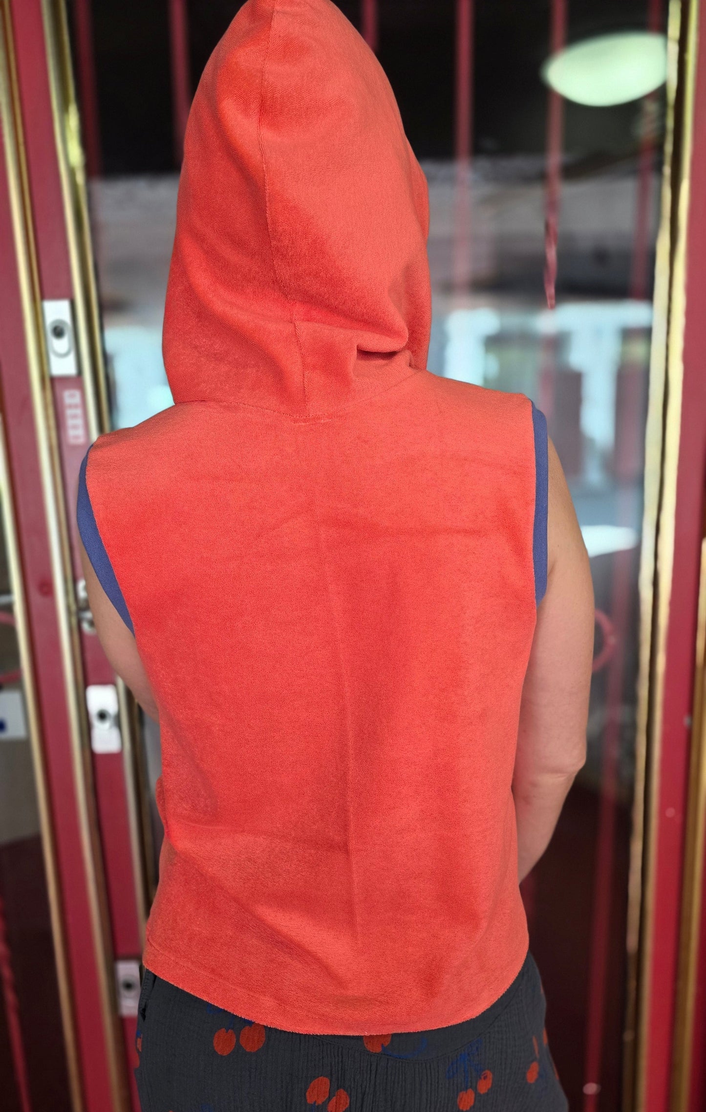 Locker sitzendes Top aus Frottee in knallrotorange, mit lila Farbakzenten an den Armausschnitten, die weiche Kapuze macht es Trendy und zeitlos trotz allem Retro Charme.