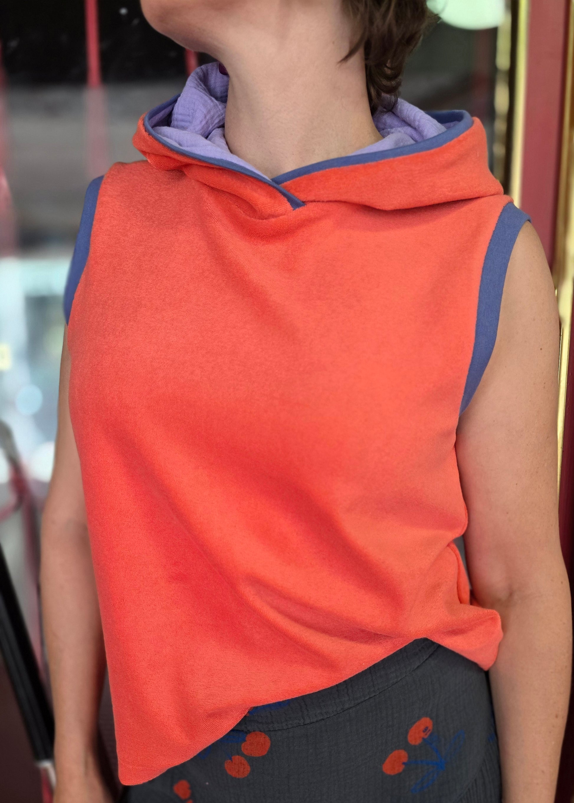 Locker sitzendes Top aus Frottee in knallrotorange, mit lila Farbakzenten an den Armausschnitten, die weiche Kapuze macht es Trendy und zeitlos trotz allem Retro Charme.