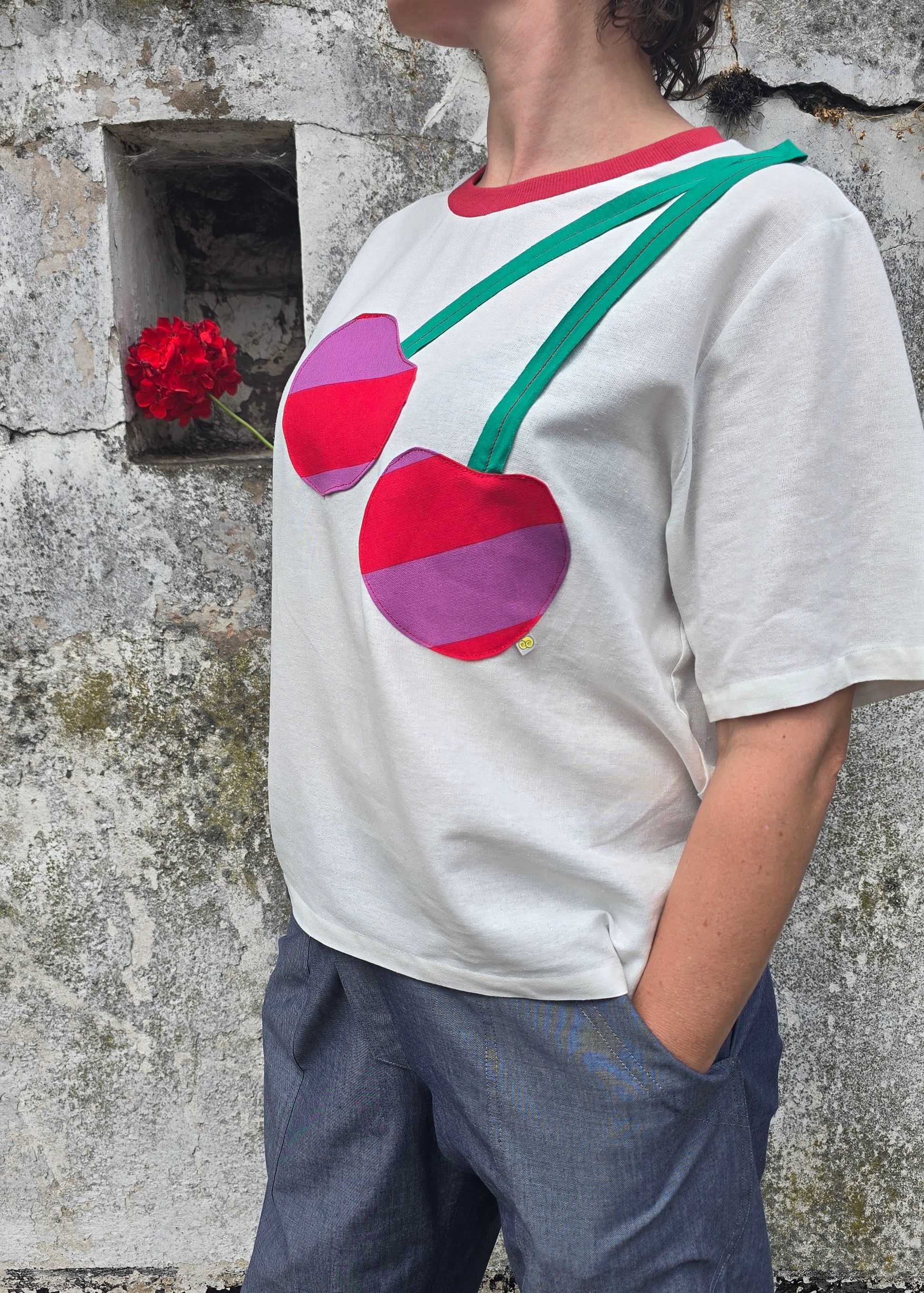 Damenshirt in Loosefit Style aus Leinenmischung in naturweiss mit seitlich über die schulter applizierte Kirsche aus gestreiftem Stoff und grünem Jersey.