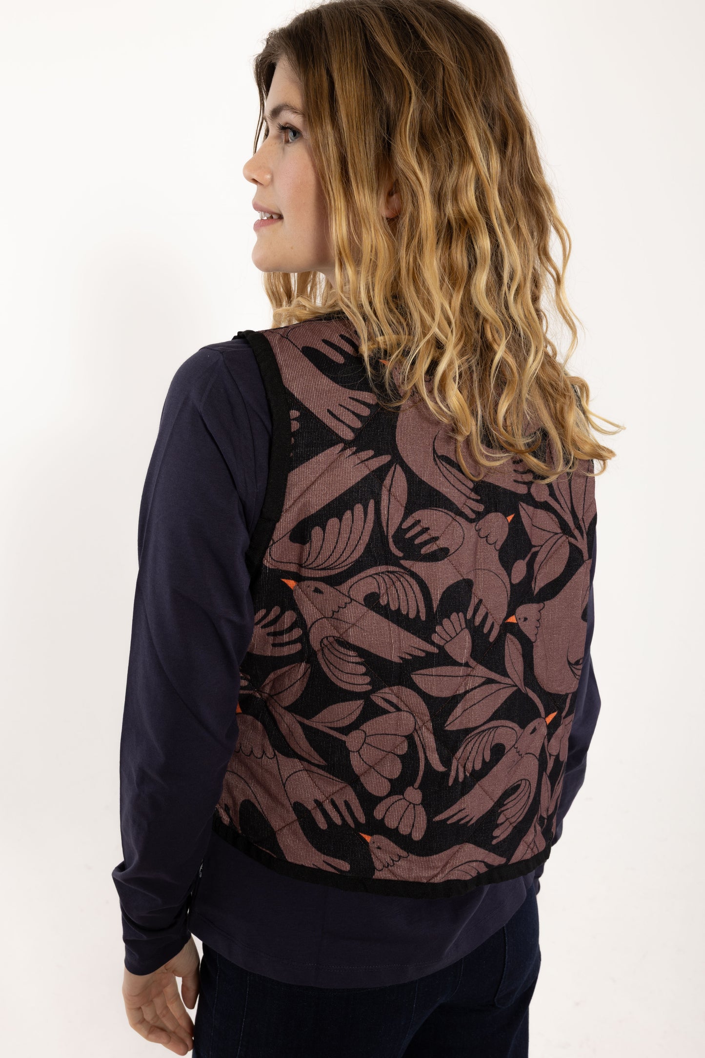 Ärmellose, wattierte Weste aus Kord mit wunderschönem Vogelprint und Blumen, gehalten in den Farben Lila und dunkelblau mit kleinsten orange Akzenten.