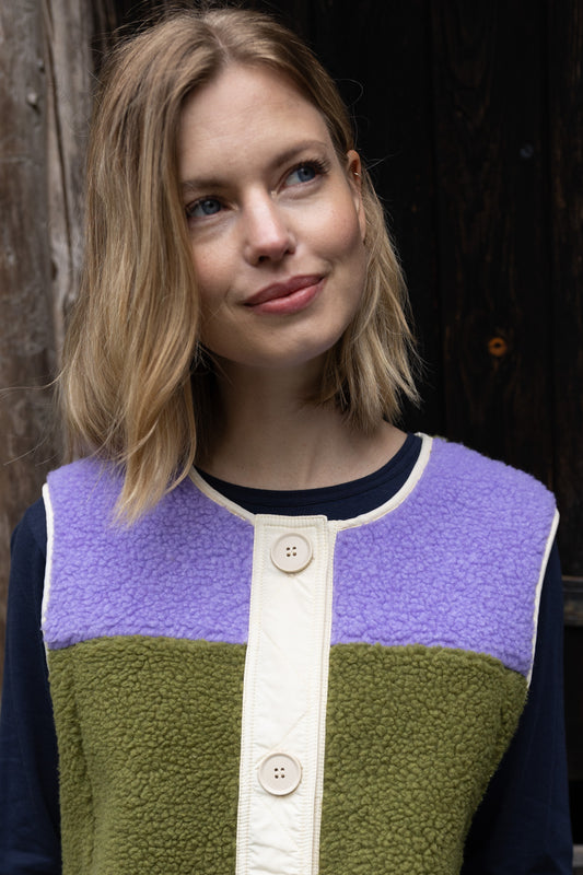 Fleece Weste im trendy Colourblock, lila und olive mit Knopfblende in Beige.
