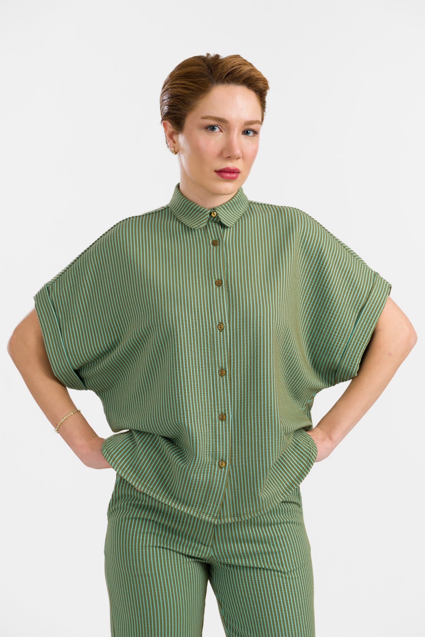 Grün-hellgrün gestreifte Seersucker Bluse in Loosefit Style mit Bubikragen und weit üerschnittenem kurzen Ärmel mit Aufschlägen- Vorne geknöpft.