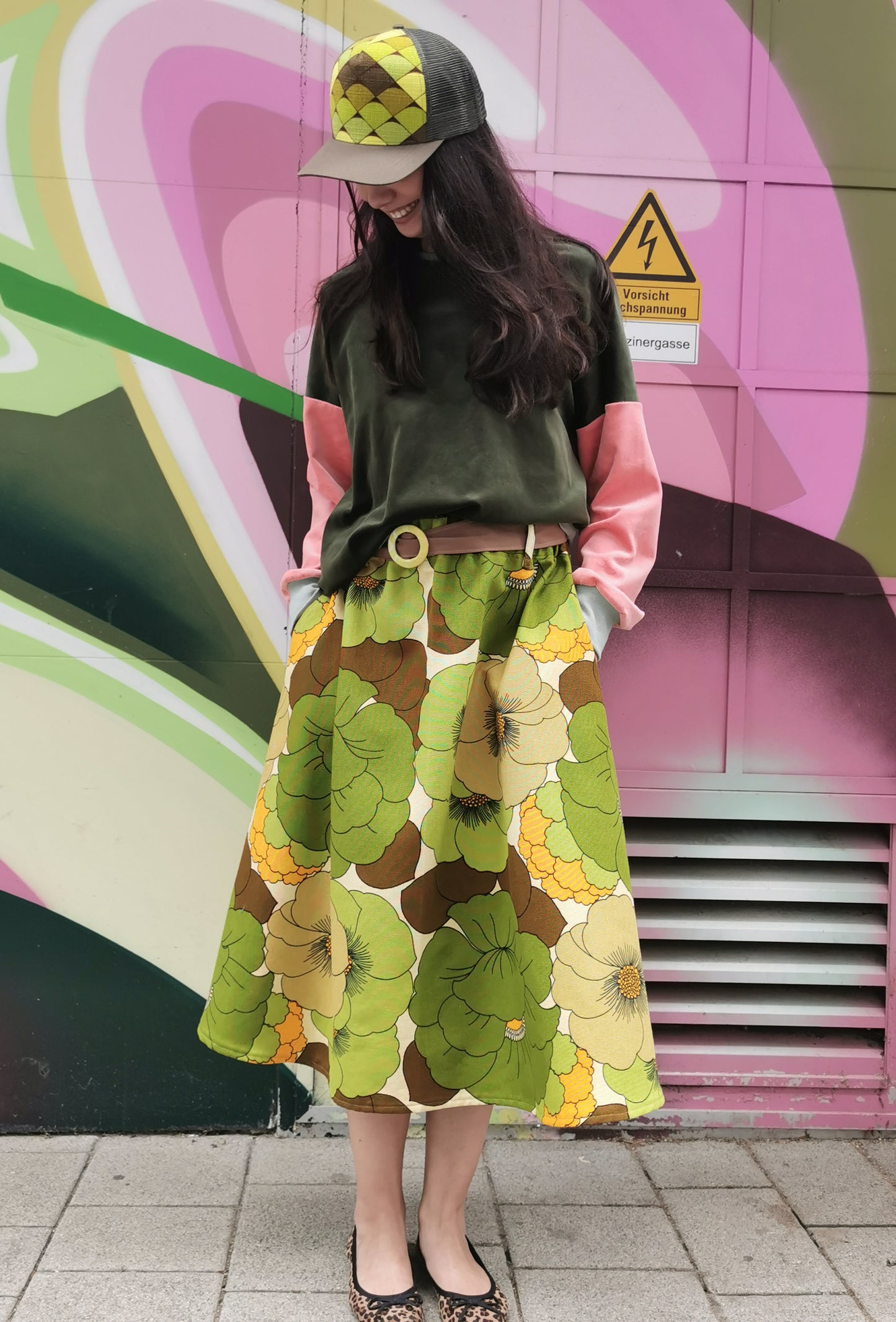 Große grüne retro Blumen auf weit schwingendem Rock mit seitlichen Eingrifftaschen und Stoffgürtel.