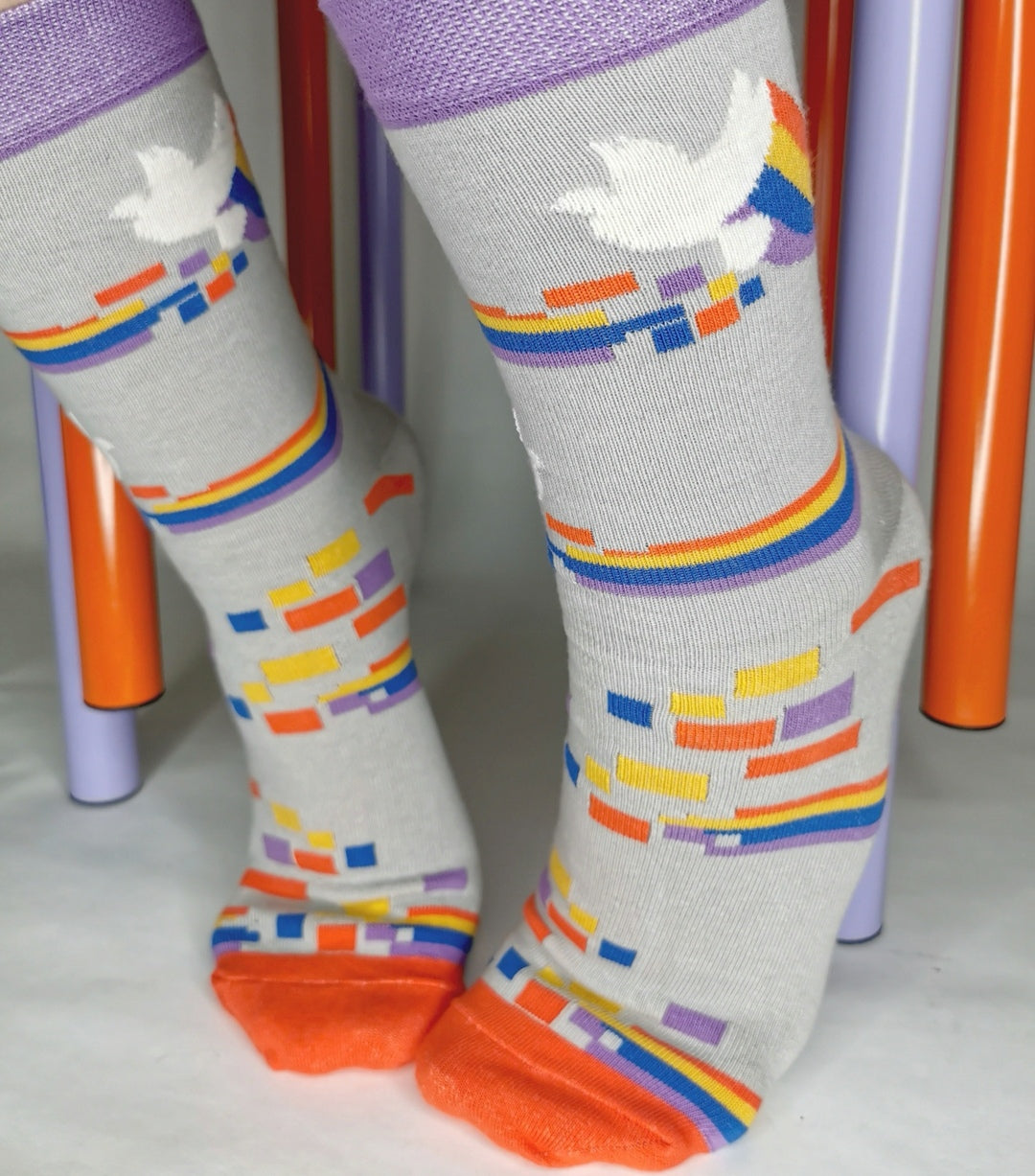 Deine Lieblingssocke zum Thema Diversity, mit Regenbogen und Friedenstaube auf hellem grau mit lila und rot Akzenten.