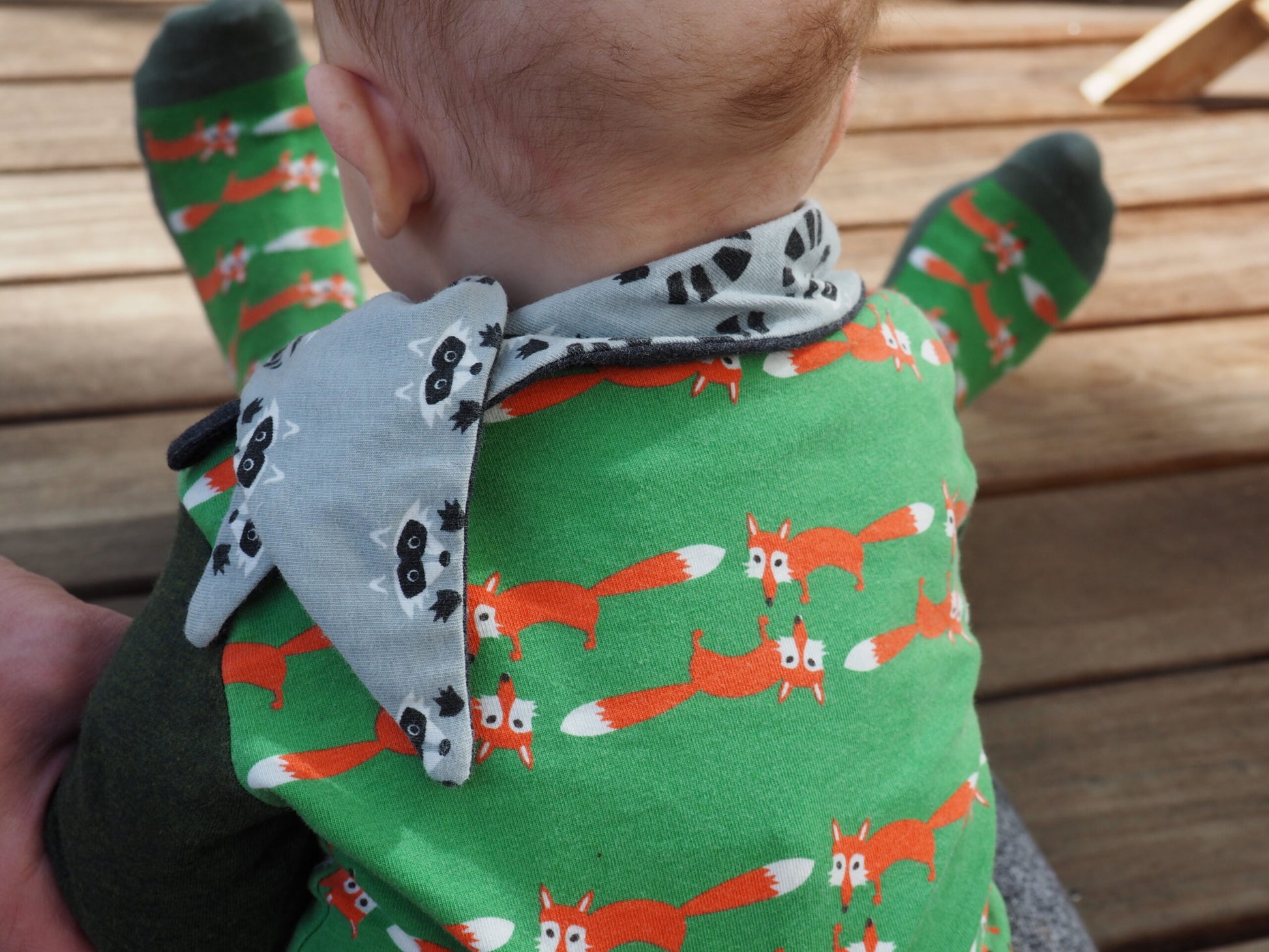 Coole Fuchs Socken in gruen, dazu passend ein Body mit gleichem Fuchsmuster und ein niedliches Waschbaer Halstuch.