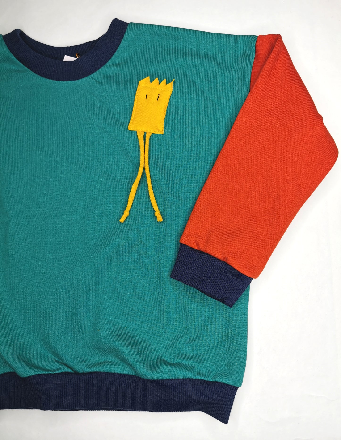 Lustiges, gelbes Strahlemännchen auf türkis orange Sweatshrt mit dunkelblauen Bündchen.