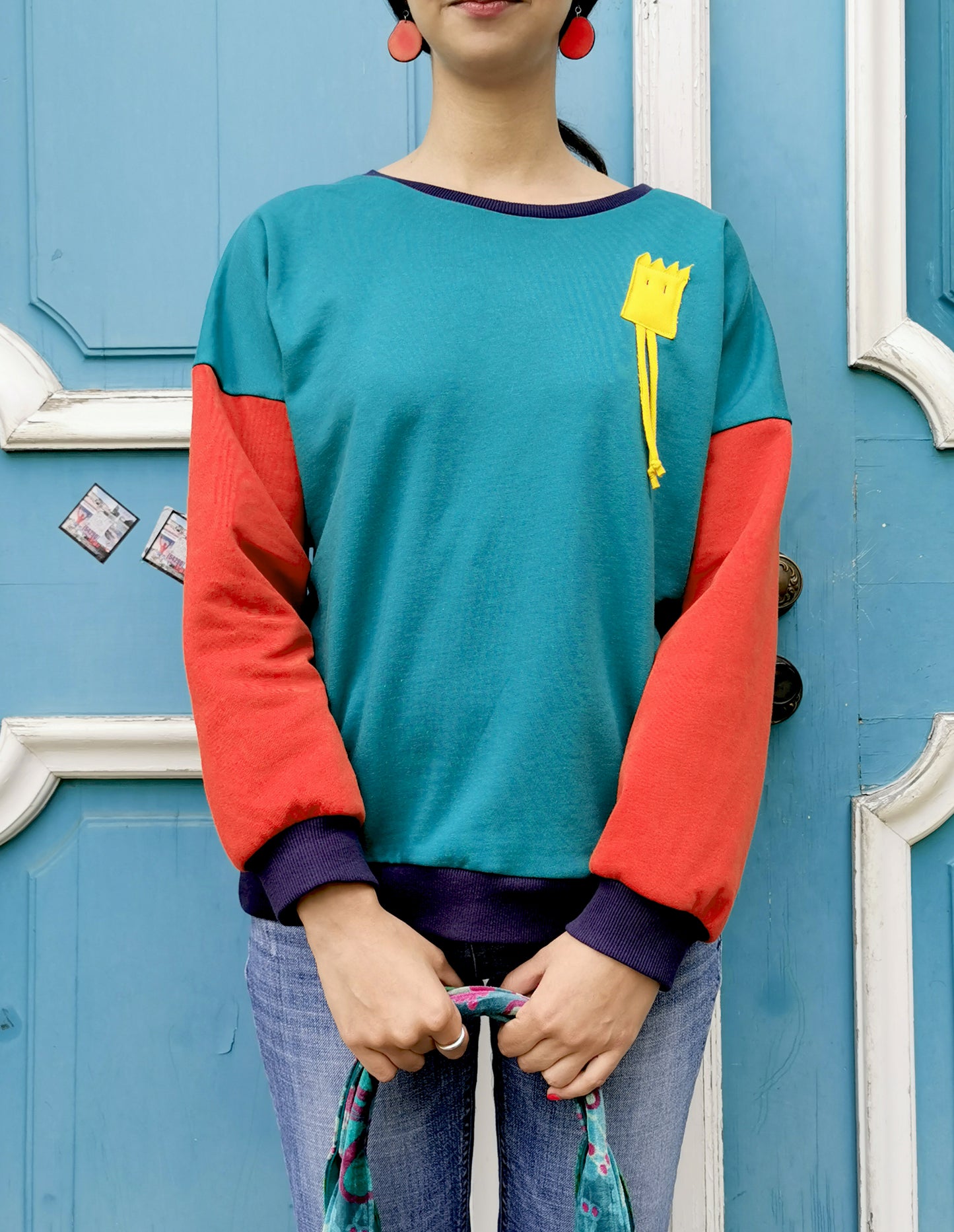 Sweatshirt mi lustigem Männchen als Applikation in Brusthöhe,türkuis und orange