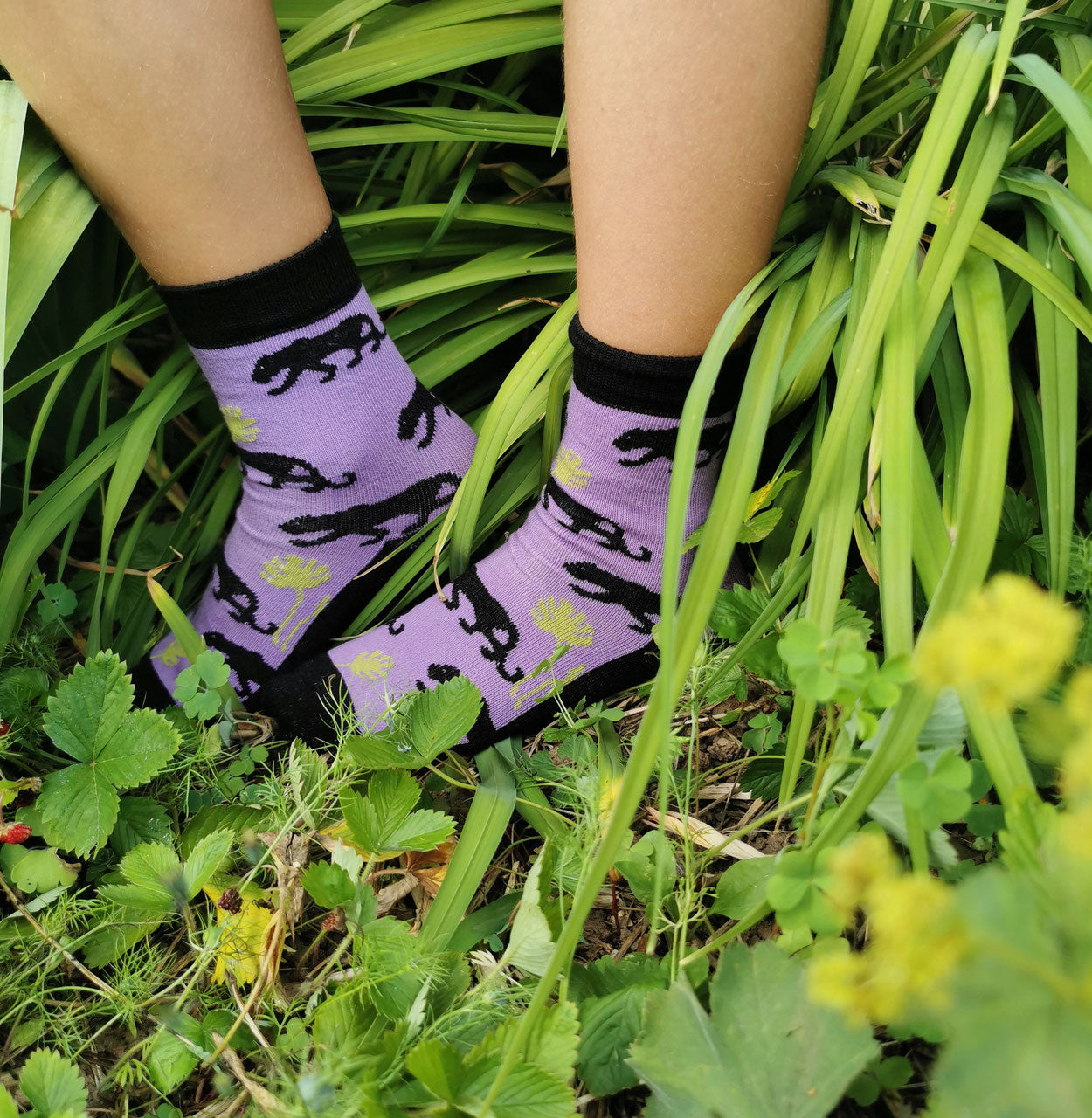 lila Socken aus Biobaumwolle mit schwarzen Pantern und Monstera Blättern.